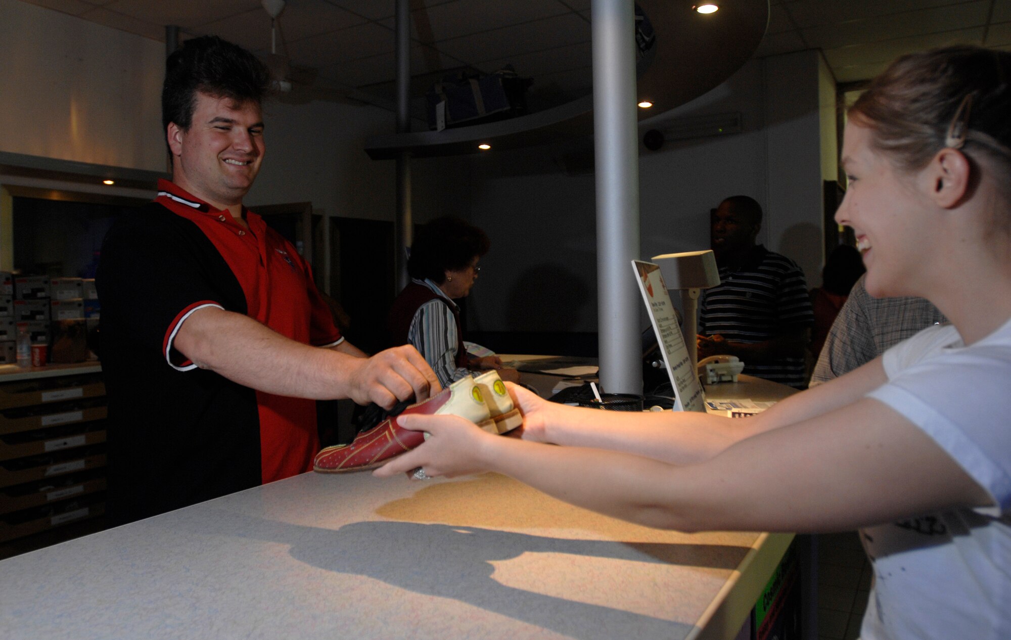 AVIANO AIR BASE, Italy --  Bowling mechanic Massimo Frits hands bowling shoes to Tabitha Mans May 17 at the Ten Pin Inn bowling center during cosmic bowling.  Cosmic bowling is open 9 p.m. to 12 a.m. every Friday and Saturday.  (U.S. Air Force photo/Airman 1st Class Ashley Wood)  