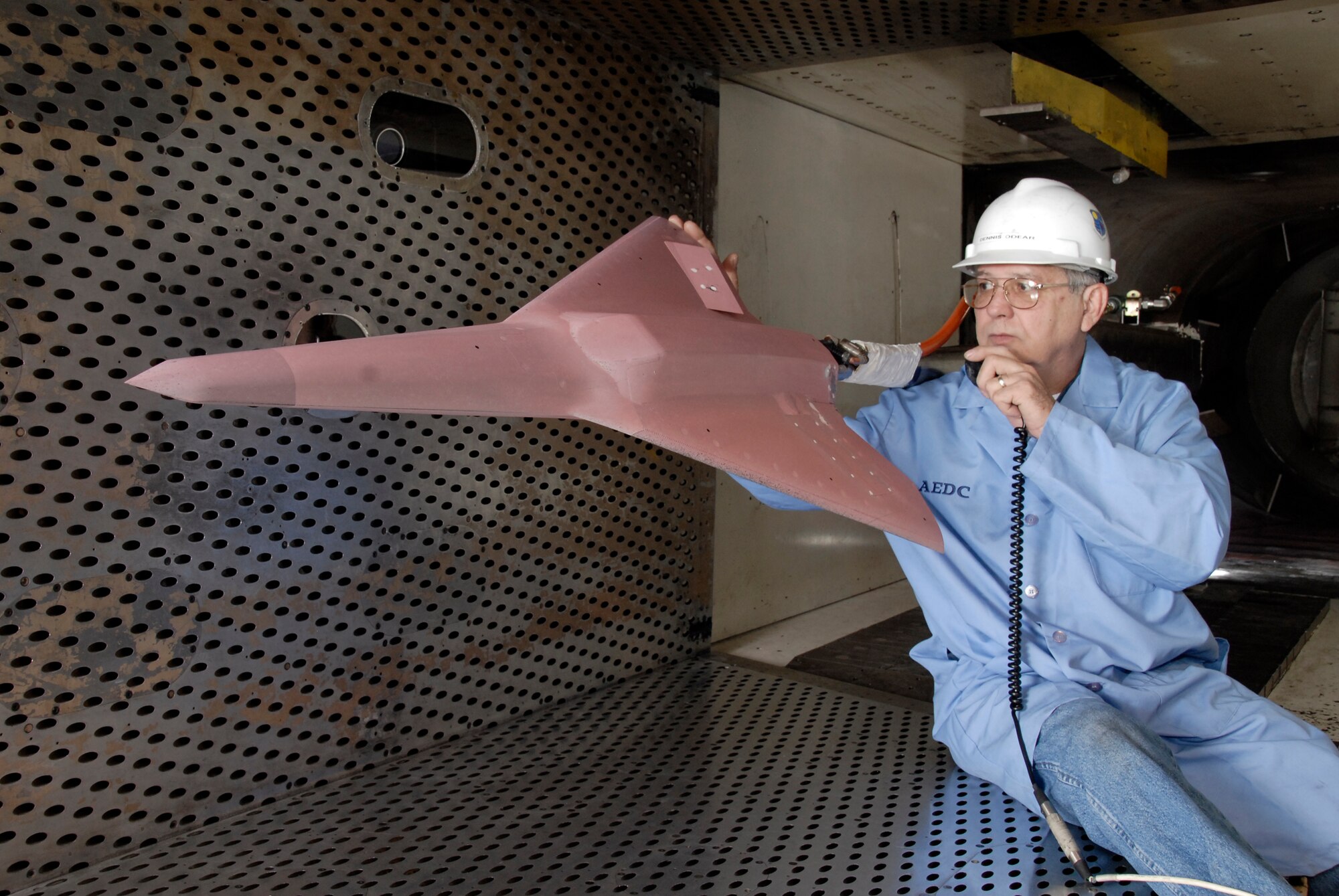 Dennis Odear, Aerospace Testing Alliance outside machinist, inpsects the tailless aircraft model in Arnold Engineering Developmnet Center's four-foot transonic wind tunnel while talking to engineers in the control room. (Photo by Rick Goodfriend)