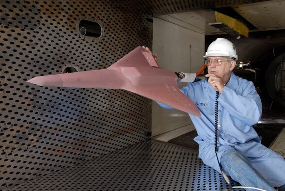 Dennis Odear, Aerospace Testing Alliance outside machinist, inpsects the tailless aircraft model in Arnold Engineering Developmnet Center's four-foot transonic wind tunnel while talking to engineers in the control room. (Photo by Rick Goodfriend)