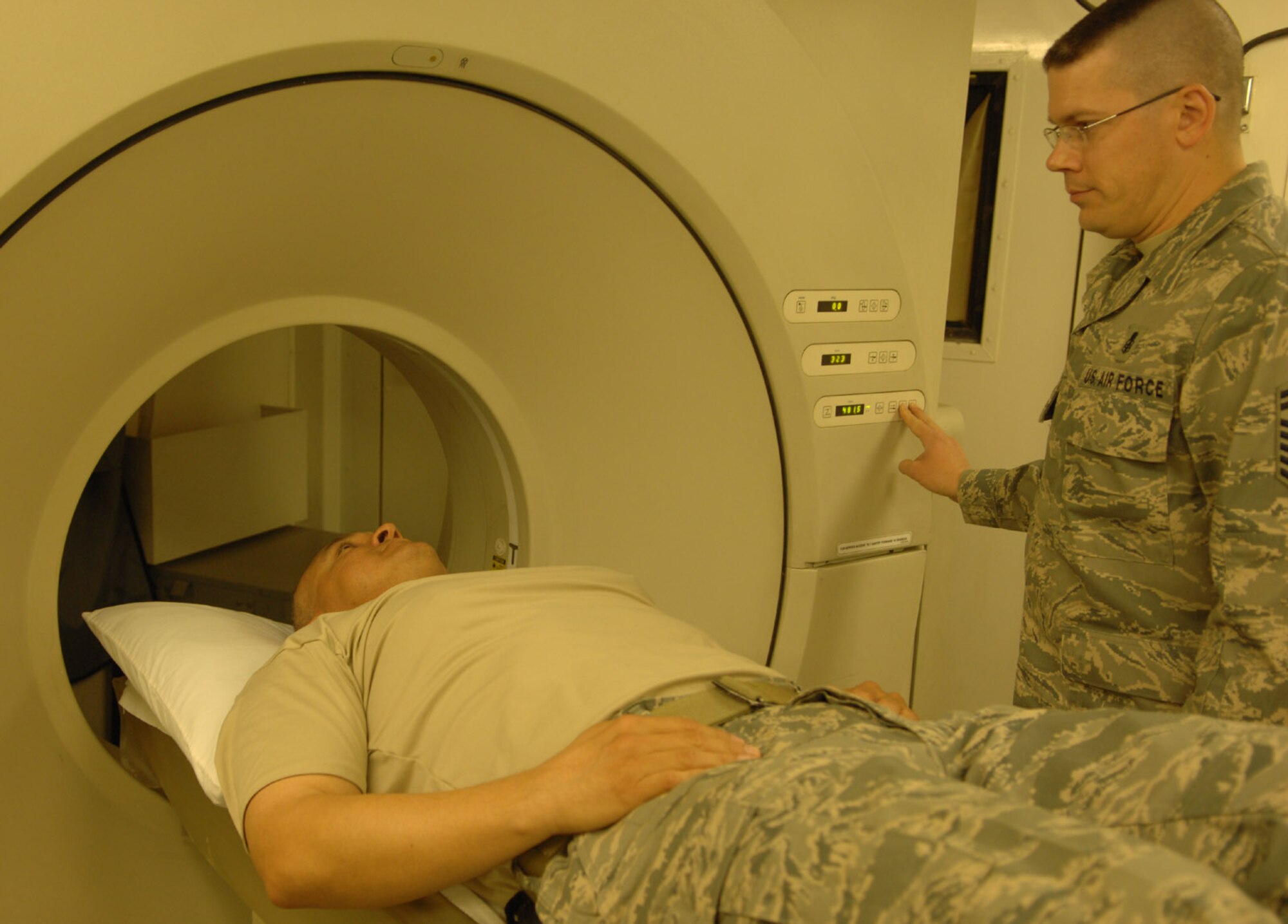 Maj. Elijio Venegas, 506th Expeditionary Medical Squadron administrator (left), and Senior Master Sgt. Russell Sneed, 506th EMEDS first sergeant, perform a computed tomography scanner demonstration May 10 here. Known as a CT scanner, the machine takes X-ray images of the body's internal areas in multi-plane slices - an improvement from typical X-ray techniques. (U.S. Air Force photo by Senior Airman Eric Schloeffel)