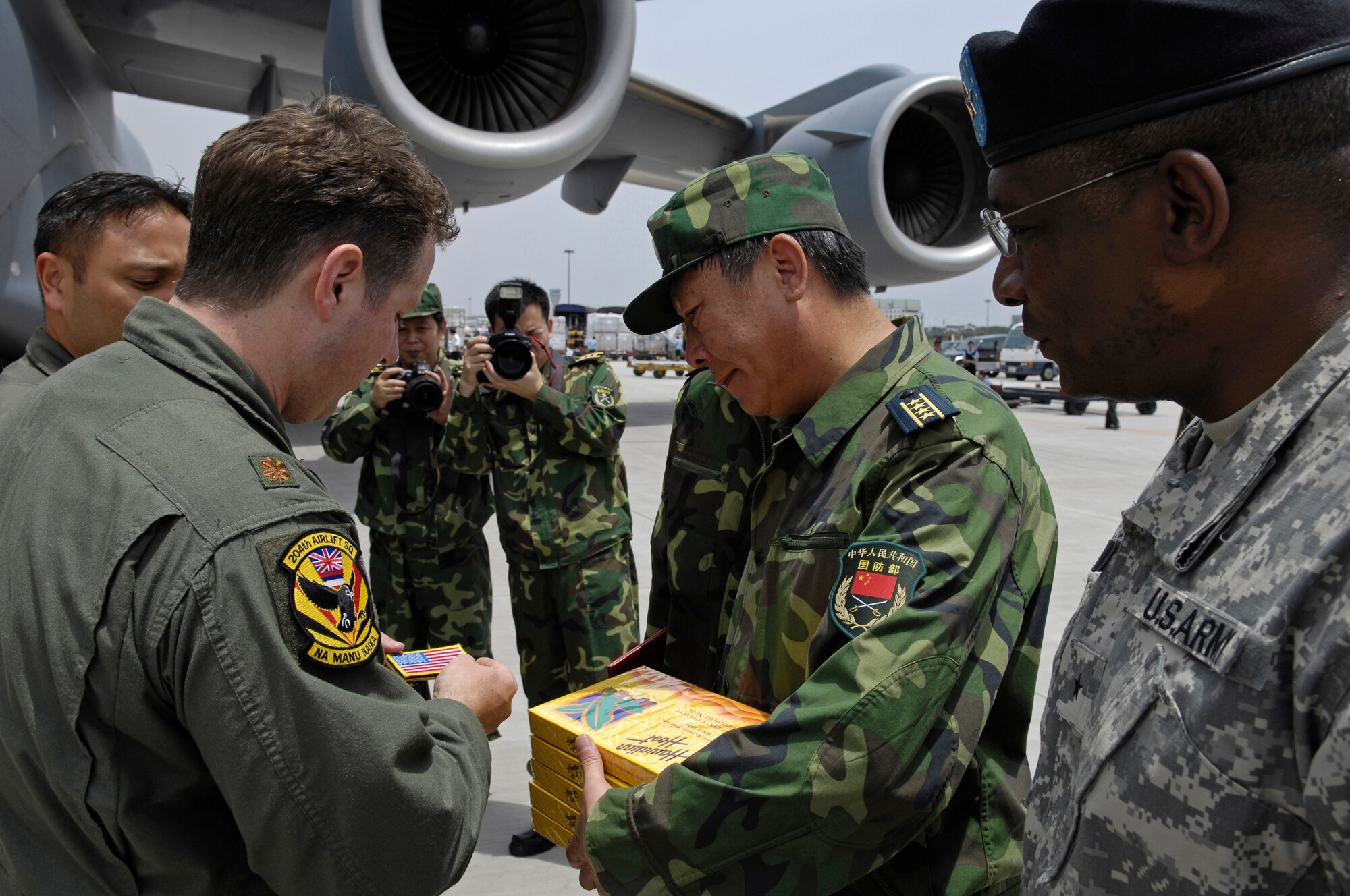 CHENGDU SHUANGLIU INTERNATIONAL AIRPORT, People’s Republic of China (May 18, 2008) – Major Anthony Davis, a C-17 pilot assigned to the Hawaii Air National Guard's 204th Airlift Squadron, presents Senior Captain GUAN Youfei, Deputy Director of the Chinese Ministry of Defense's Foreign Affairs Office, with gifts of traditional Hawaiian chocolates and an American Flag patch at Chengdu Shuangliu International Airport in China on May 17, 2008. Major Davis was the aircraft commander of one of the C-17s, which carried nearly 100,000 pounds of relief supplies. Also pictured is Brig. Gen. Charles W. Hooper, U.S. Defense Attache. The United States Pacific Command support of earthquake relief efforts was authorized by Secretary of Defense Robert Gates, in support of the U.S. Department of State. (US Air Force photo / Tech. Sgt. Chris Vadnais)