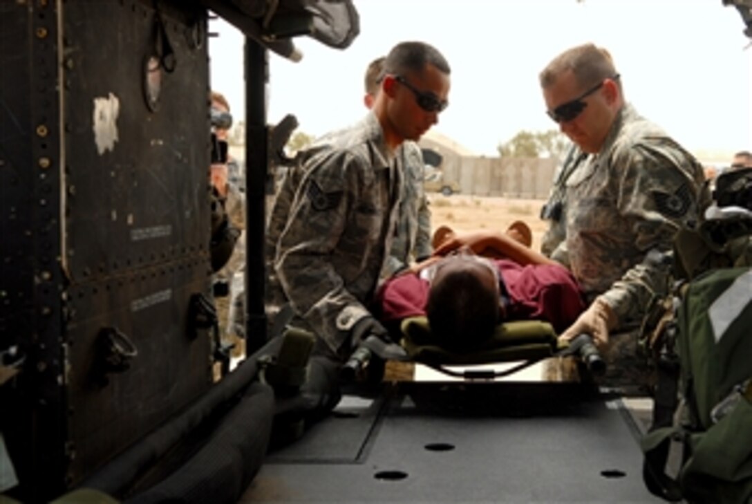 U.S. Air Force Staff Sgt. David Hernandez and Tech. Sgt. Joseph Vergona, both contingency aeromedical staging facility medical technicians with the 332nd Expeditionary Aeromedical Squadron, load an Iraqi trauma patient onto an Iraqi air force Huey II helicopter at Balad Air Base, Iraq, on May 14, 2008.  Iraqi airmen will transport the patient to the U.S. Army's 86th Combat Support Hospital in Baghdad, Iraq.  The mission will be the first medical evacuation mission flown by the Iraqi air force.  