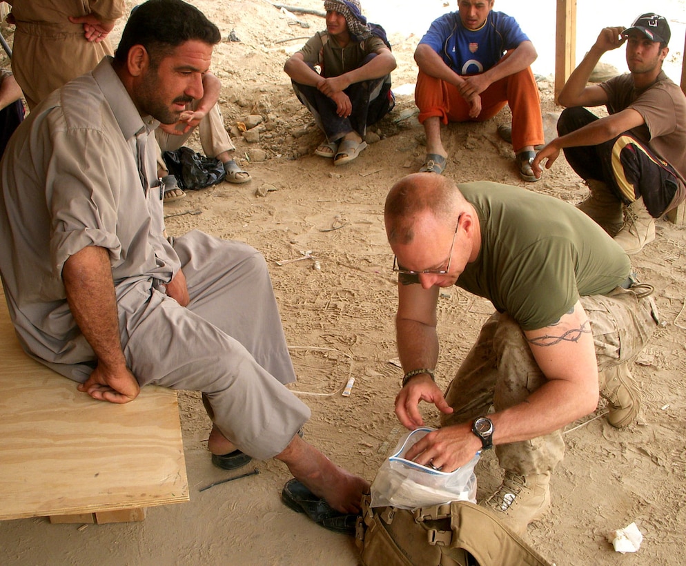 HM2 Adam F. Kinney, a Navy Corpsman with Echo Co., 2nd Bn., 24th Marines, provides medical aid to a local Iraqi man. Kinney is a criminal attorney in Elizabethtown, Ky., when not either activated or drilling with his reserve battalion.::r::::n::   ::r::::n::