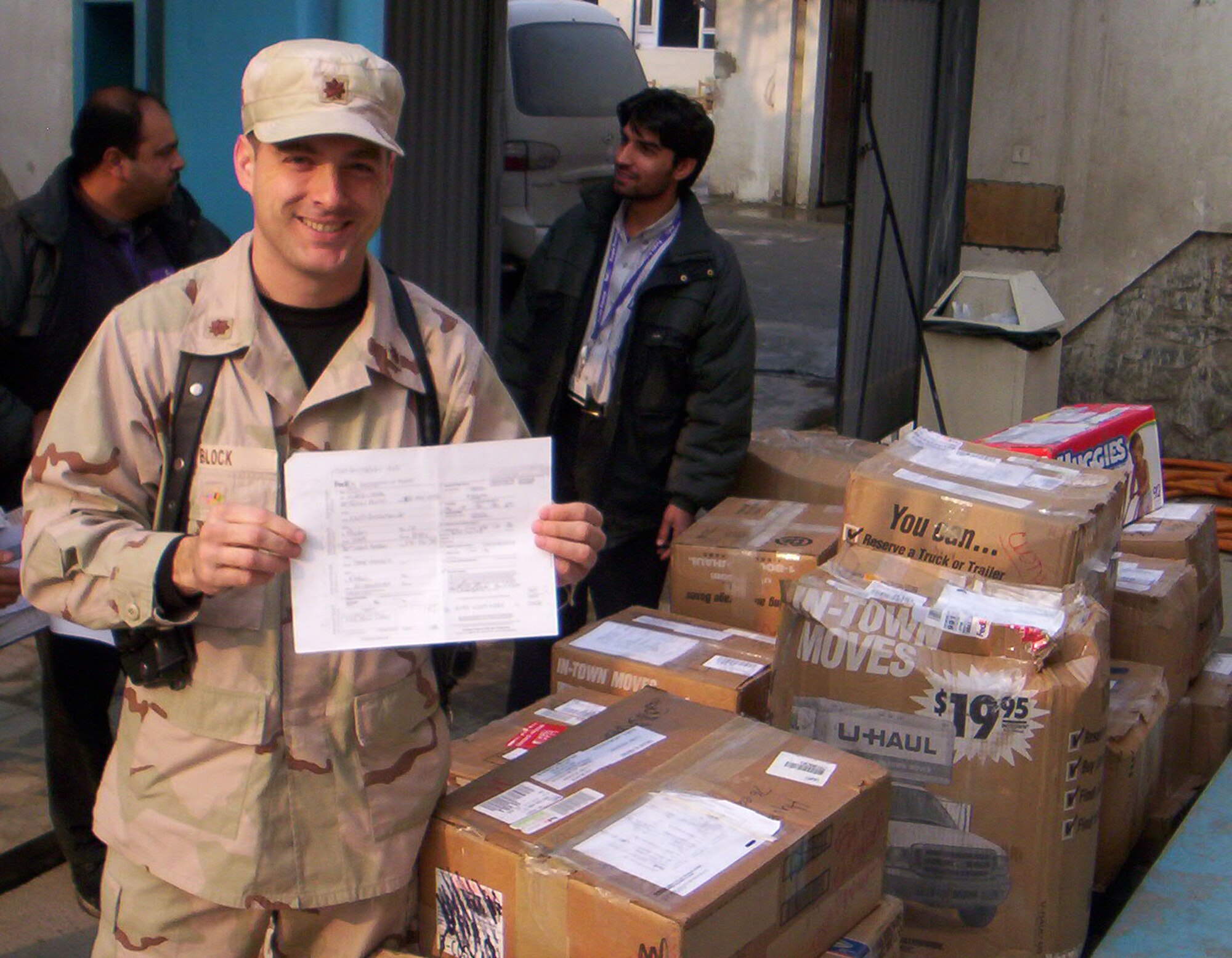 MINOT AIR FORCE BASE, N.D. -- Maj. Jay Block, 91st Maintenance Group chief of quality assurance, poses with the shipping invoice signed in Colorado by his wife, Kelli Block, and boxes of clothing and school supplies she helped donate. The items, which arrived in Kabul, Afghanistan, in 2005, were donated to a local orphanage. After hearing the story recently, a group of North Dakota insurance agents and financial planners in Minot raised almost $14,000 in 30 minutes for the orphanage. (Courtesy photo)         