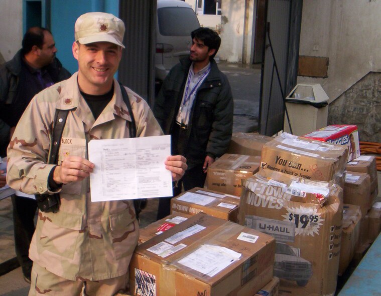 MINOT AIR FORCE BASE, N.D. -- Maj. Jay Block, 91st Maintenance Group chief of quality assurance, poses with the shipping invoice signed in Colorado by his wife, Kelli Block, and boxes of clothing and school supplies she helped donate. The items, which arrived in Kabul, Afghanistan, in 2005, were donated to a local orphanage. After hearing the story recently, a group of North Dakota insurance agents and financial planners in Minot raised almost $14,000 in 30 minutes for the orphanage. (Courtesy photo)         