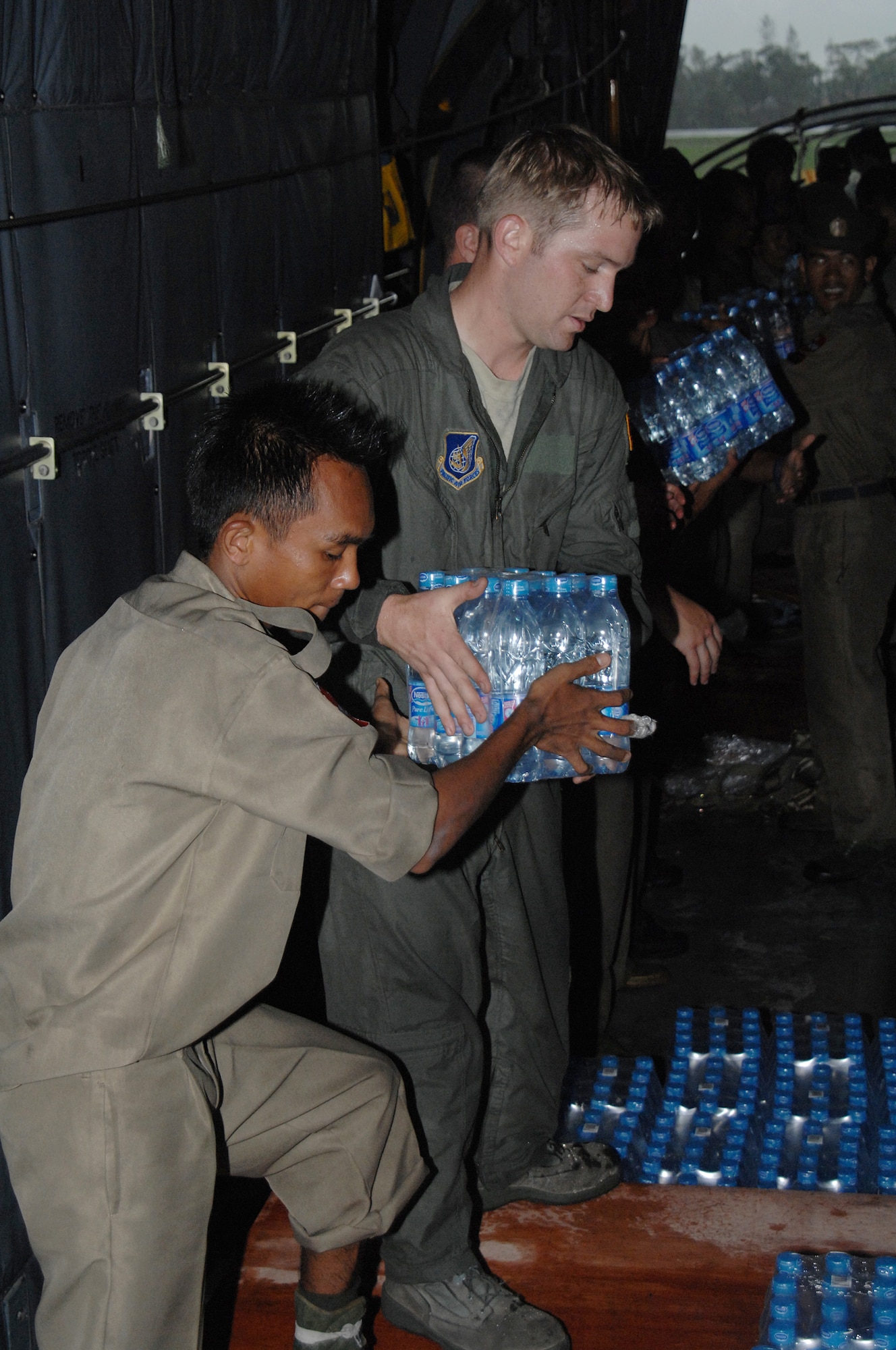 YANGON, Burma--  Staff Sgt Joseph Strutton, helps a Burmese military member transfer water from a pallet during a delivery May 19. Sergeant Strutton is assigned to the 374th Airlift Wing from Yokota Air Base, Japan. Approximately 15,000 lbs of water, water containers and mosquito netting were unloaded at Yangon International Airport. The Airmen are deployed in support of Operation Caring Response. (U.S. Air Force photo by Senior Airman Sonya Croston)