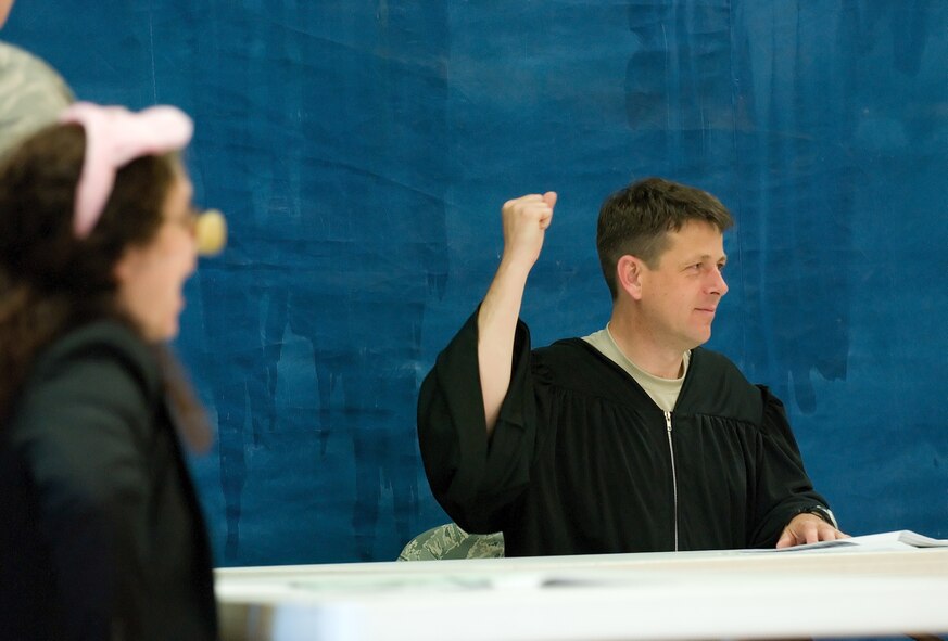 Lt. Col. Wes Moore, 436th Airlift Wing Staff Judge Advocate, hammers the table as he tries to restore order during a mock trial May 2 at Maj. George S. Welch Elementary School.  In the foreground, Curly Pig, played by Carmel-Ann Feliciani, 436th AW chief of general law, attempts to rebut statements made by the Big Bad Wolf.  (U.S. Air Force Photo/Jason Minto)