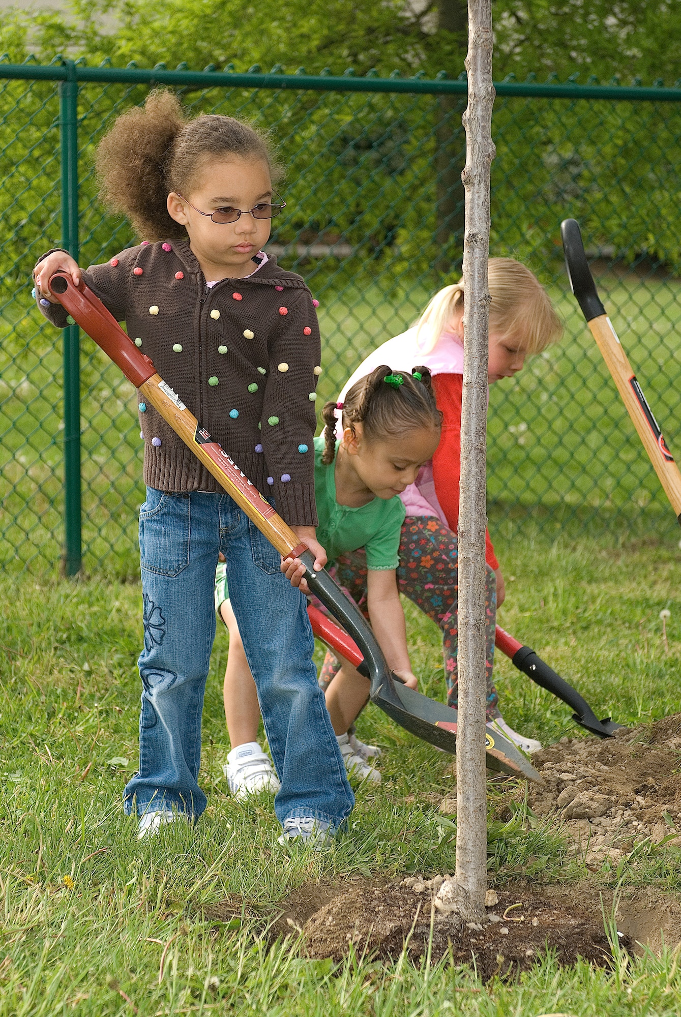 From left:   Jadon Broadnax, Naomi Nelson and Haley Devine plant a tree at the Child Development Center May 2 for Arbor Day.  The tree planting ceremony was held as part of the ceremony recognizing Dover Air Force Base as the recipient of the Tree City USA Award, given to communities that meet standards set out by The Arbor Day Foundation and the National Association of State Foresters. (U.S. Air Force Photo/Roland Balik)