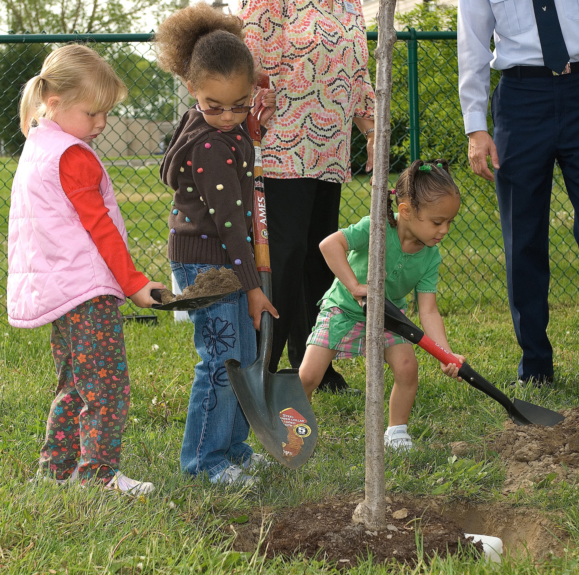 From left:  Haley Devine, Jadon Broadnax, and Naomi Nelson  plant a tree at the Child Development Center May 2 for Arbor Day.  The tree planting ceremony was held as part of the ceremony recognizing Dover Air Force Base as the recipient of the Tree City USA Award, given to communities that meet standards set out by The Arbor Day Foundation and the National Association of State Foresters. (U.S. Air Force Photo/Roland Balik)