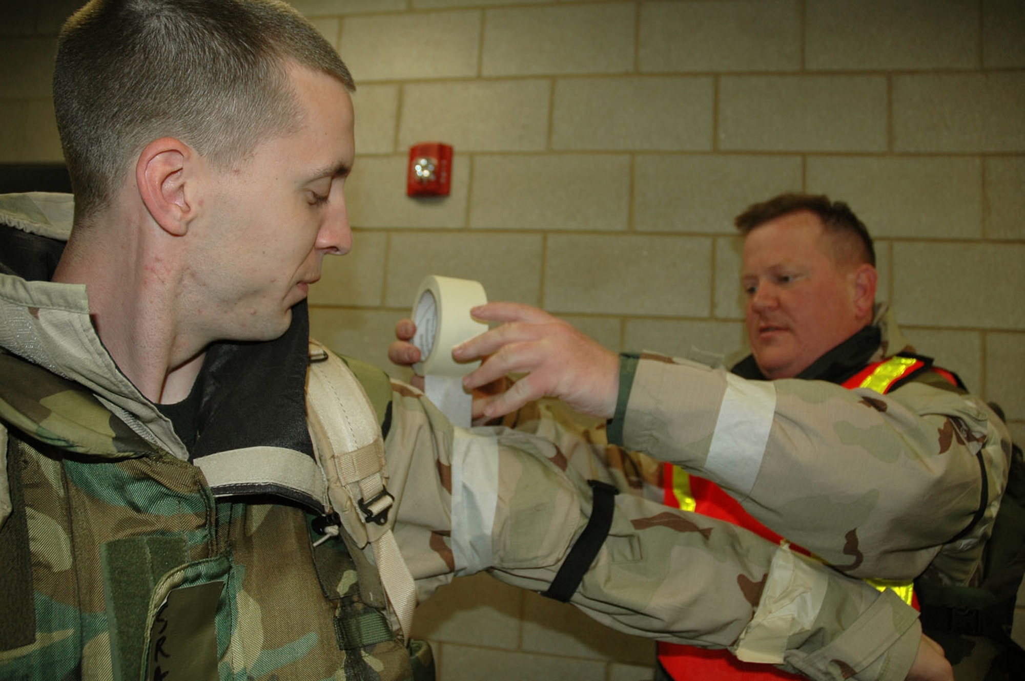 Master Sgt. Eric Getz, 436th Airlift Wing Safety Office, places simulated M-9 tape on Senior Airman Christopher Uppling, 436th AW Command Post, April 22 in Alpena, Mich.  M-9 tape is used to detect contaminants in the environment.  During exercises and wartime, it's essential Airmen work together to safeguard each other and accomplish the mission.  (U.S. Air Force Photo/Master Sgt. Melissa Phillips)