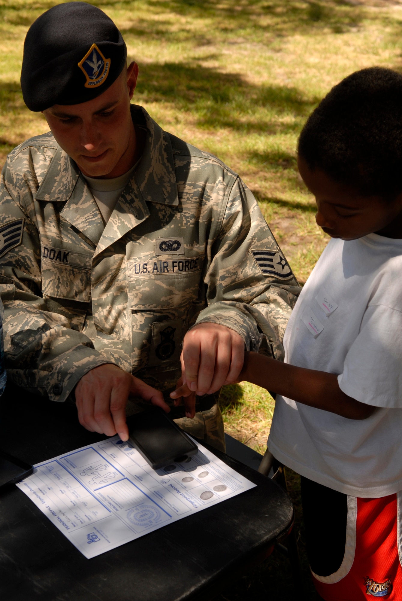 Staff Sgt. Kevin Doak, a resource protection program manager with the 30th Security Forces Squadron, fingerprints a child during the Police Week BBQ Friday at Cocheo Park. (U.S. Air Force photo/Airman 1st Class Christian Thomas) 
