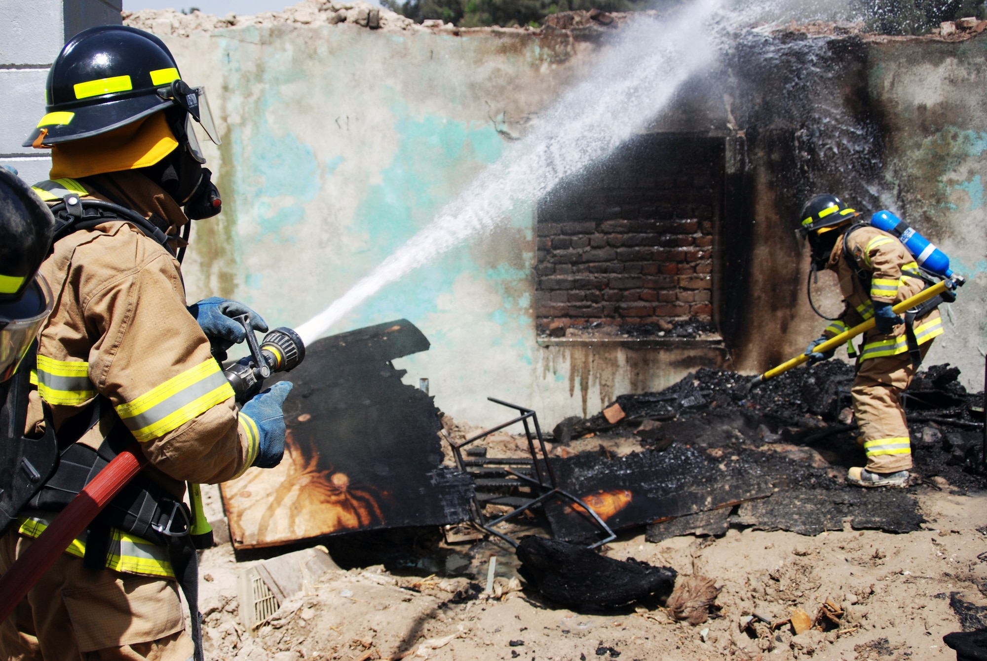 Members of the Afghan National Army Air Corps battle flames in an abandoned building during an exercise May 12 at Kabul, Afghanistan, during a firefighting course. The four-month course was mentored by Master Sgt. Michael Marascia of the Combined Air Power Transition Force. More than 1,500 firefighters will be trained in the next two years. (U.S. Air Force photo/Petty Officer 1st Class Douglas Mappin) 