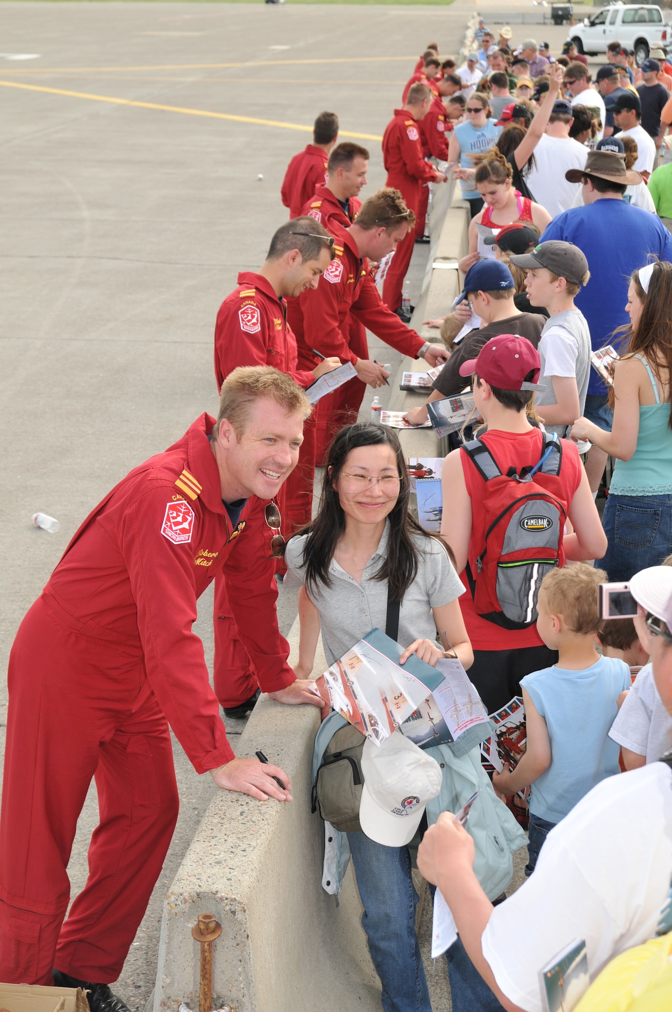 Canadian Snowbirds Commanding Officer Maj. Robert Mitchell poses for a photo with a fan while the rest of his team signs autographs following their second performance at Malmstrom in two days May 18. The Snowbirds were the highlight event of the Air Show and Open House. (U.S. Air Force photo/John Turner)