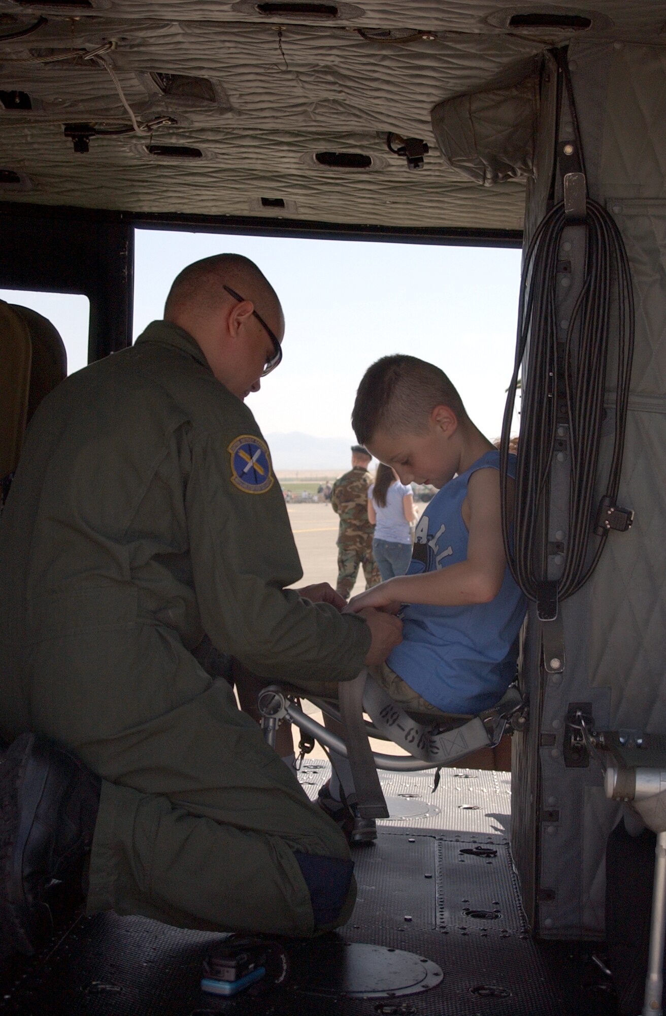 Staff Sgt. Eric Rodriguez straps Little Warrior Samuel, 9, into the jump seat on the UH-1N "Huey" helicopter during Malmstrom Air Force Base's Air Show and Open House May 17. (U.S. Air Force photo/Valerie Mullett)