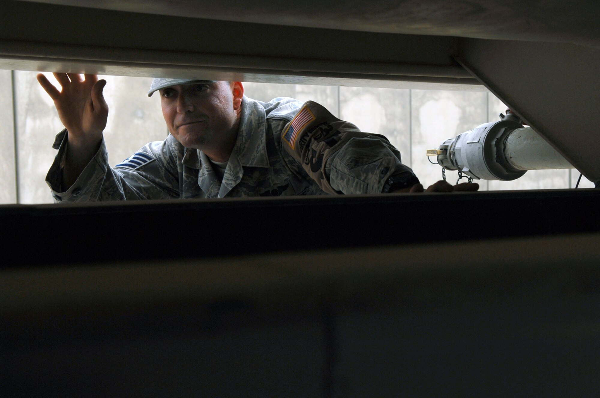 Staff Sgt. Jesse Wright looks underneath a water truck passing through a gate for questionable items May 17 at Balad Air Base, Iraq. Preventing unauthorized items from entering the base via vehicles or personnel ensures the safety of those assigned to the base. Sergeant Wright is a 332nd Expeditionary Security Forces Squadron force protection inspector deployed from Altus Air Force Base, Okla. (U.S. Air Force photo/Senior Airman Julianne Showalter) 
