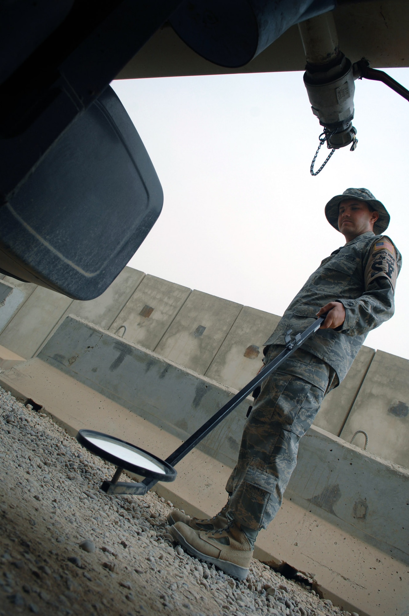 Senior Airman Branden Hall looks at the undercarriage of a truck passing through a gate May 17 at Balad Air Base, Iraq. Preventing unauthorized items from entering the base via vehicles or personnel ensures the safety of those assigned to the base. Airman Hall is a 332nd Expeditionary Security Forces Squadron force protection inspector deployed from Luke Air Force Base, Ariz. (U.S. Air Force photo/Senior Airman Julianne Showalter) 
