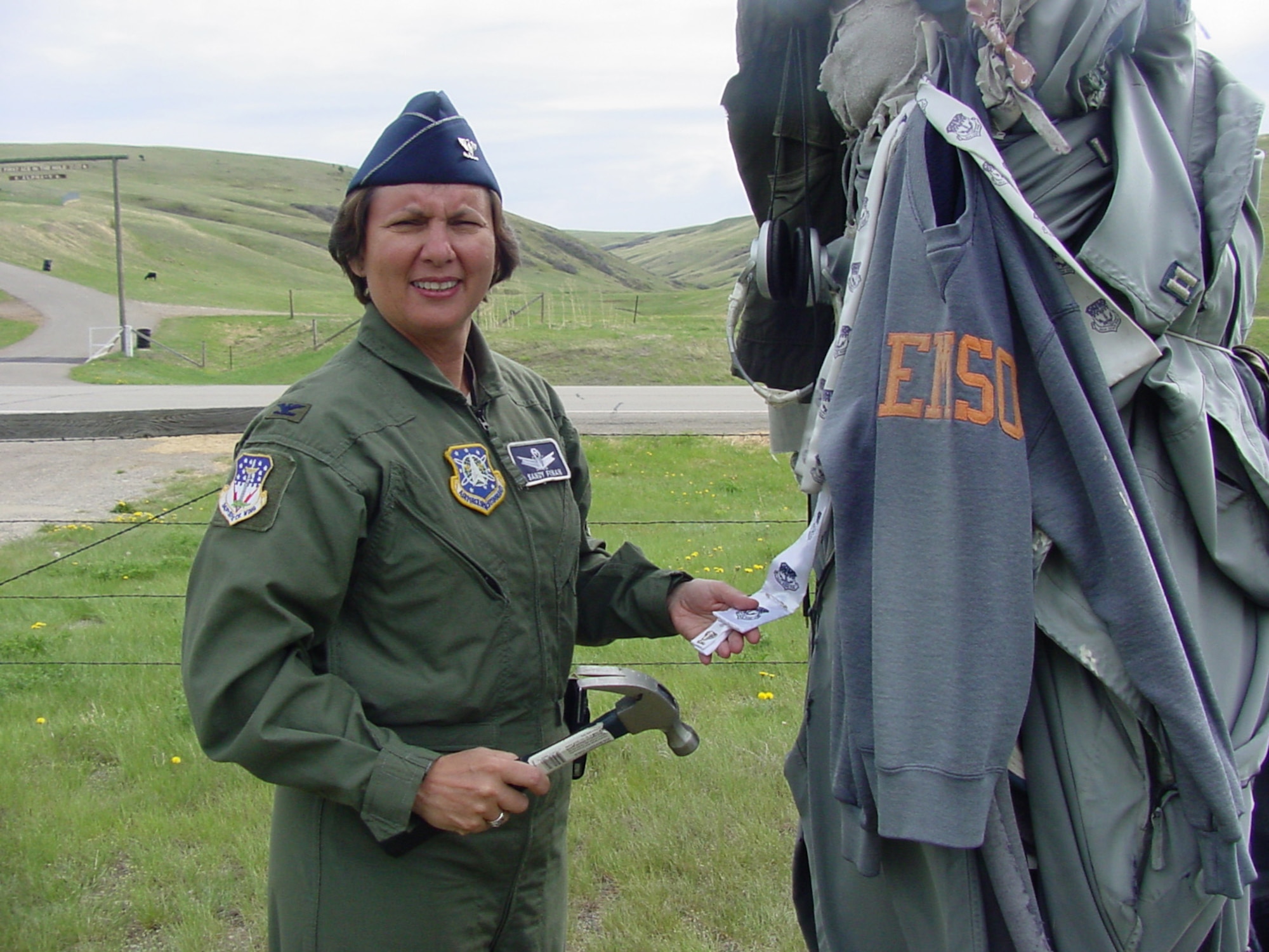 Col. Sandy Finan, 341st Space Wing commander, displays her 341st Space Wing scarf after nailing it to a post across from Alpha-01 missile alert facility May 19. 
It is a tradition amongst the members of the 10th MS assigned to Alpha-01 to attach scarves, uniforms and other personal effects to the pole upon the completion of their final alert. The commander now has two scarves affixed to the 10th Missile Squadron landmark, as she was once a missileer assigned to the 10th MS, and manned her last alert June 24, 1991. The commander left Malmstrom May 21 for her new assignment at Peterson Air Force Base, Colo. (U.S. Air Force photo/ Airman 1st Class Dillon White) 