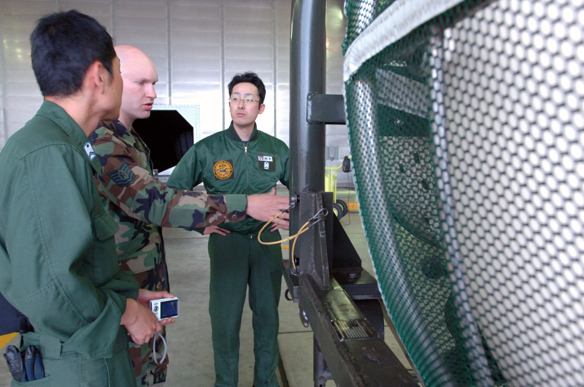 Tech. Sgt. Marcus Sydow briefs Japanese Air Self Defense Force Tech. Sgt. Takuma Ota (left) and Staff Sgt. Masanobu Suzuki (right) about 35th Fighter Wing equipment May 15 at Misawa Air Base, Japan. Sergeant Sydow is the propulsion shop nonpowered age NCO in charge. (U.S. Air Force photo/Senior Airman Robert Barnett) 
