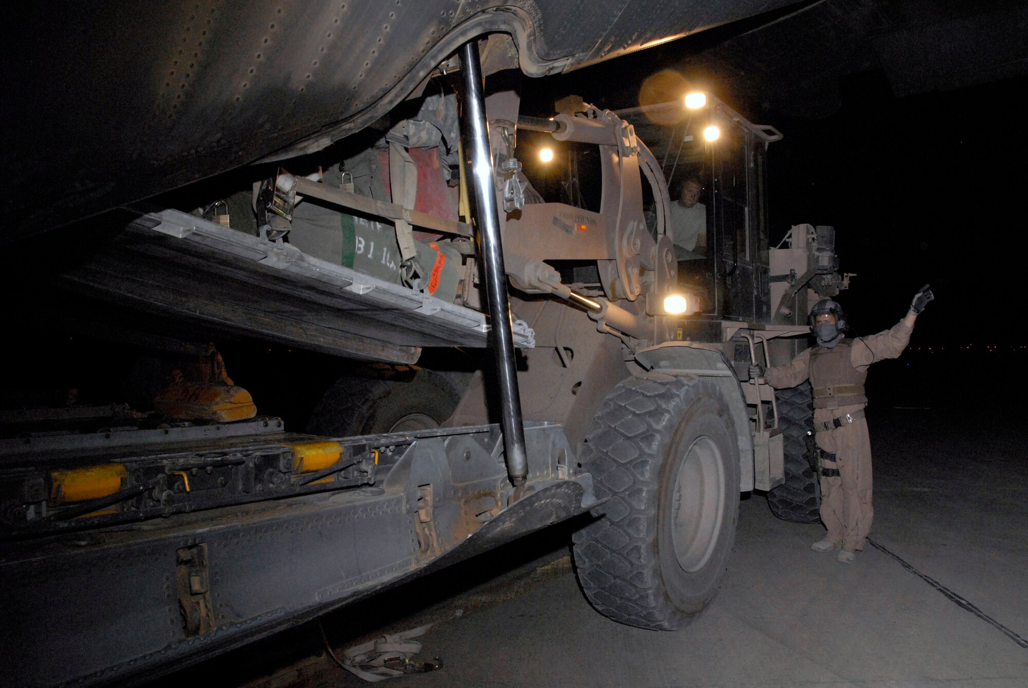 Staff Sgt. Gabriel Molanders martials in Airman 1st Class Bryan Rogers who's delivering a baggage pallet for a group of Soldiers from Fort Benning, Ga., departing Iraq May 13. Sergeant Molanders is a C-130 Hercules loadmaster with the 737th Expeditionary Airlift Squadron deployed from Dyess Air Force Base, Texas, and Airman Rogers is an aerial porter with the 447th Air Expeditionary Group deployed from McGuire AFB, N.J. (U.S. Air Force photo/Tech. Sgt. Michael O'Connor) 
