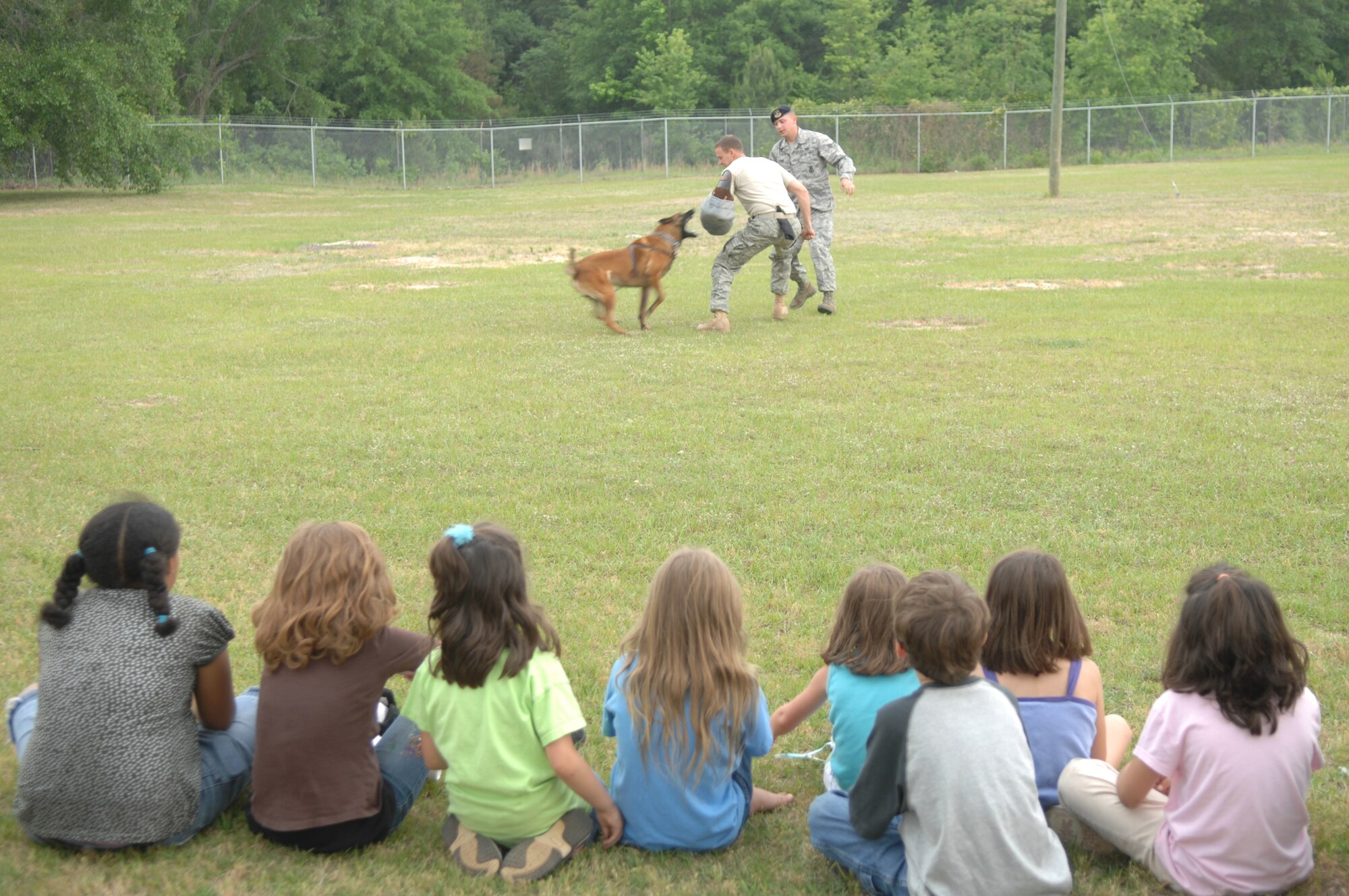 SHAW AIR FORCE BASE, S.C. -- Senior Airman Jeremy Page observes Staff Sgt. Randy Blair, both 20th Security Forces Squadron military working dog handlers, and Hhero, 20th SFS military working dog, demonstrate how to take down a suspect resisting arrest during a block party in observance of Police Week May 16. May 15 is National Peace Officers Memorial Day and the week containing that day is National Police Week since President John F. Kennedy signed Public Law 87-726 Oct. 1, 1962. (U.S. Air Force photo/Staff Sgt. Nathan Bevier)