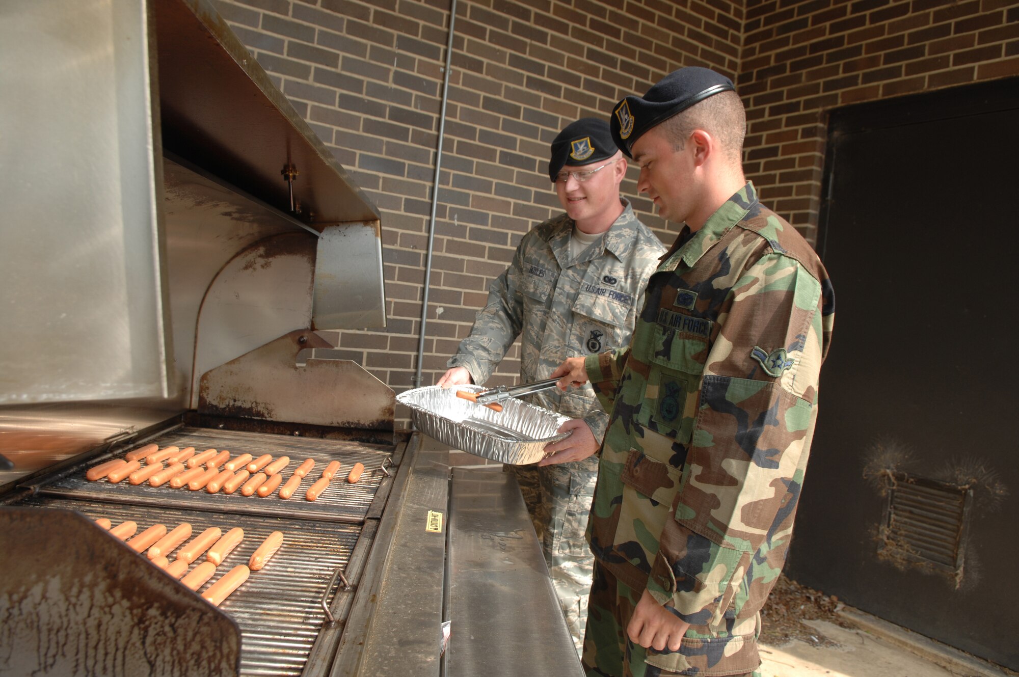 SHAW AIR FORCE BASE, S.C. -- Airman Cameron Biddix, 20th Security Forces Squadron entry controller, and Senior Airman Alexander Boyles, 20th SFS patrolman, prepare hotdogs for a block party in observance of Police Week May 16. May 15 is National Peace Officers Memorial Day and the week containing May 15 is National Police Week since President John F. Kennedy signed Public Law 87-726 Oct. 1, 1962. (U.S. Air Force photo/Staff Sgt. Nathan Bevier)