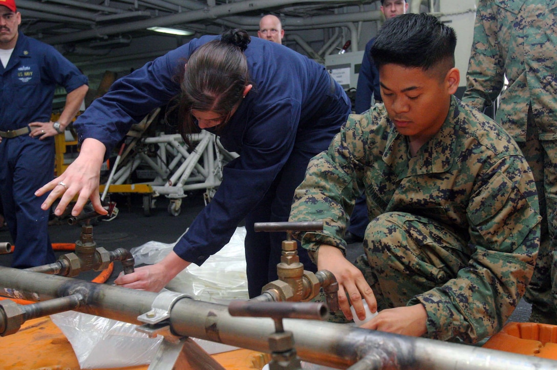 U.S. Marine Corps Lance Cpl. Alan Bundoc replaces a cap on a 16-liter ...