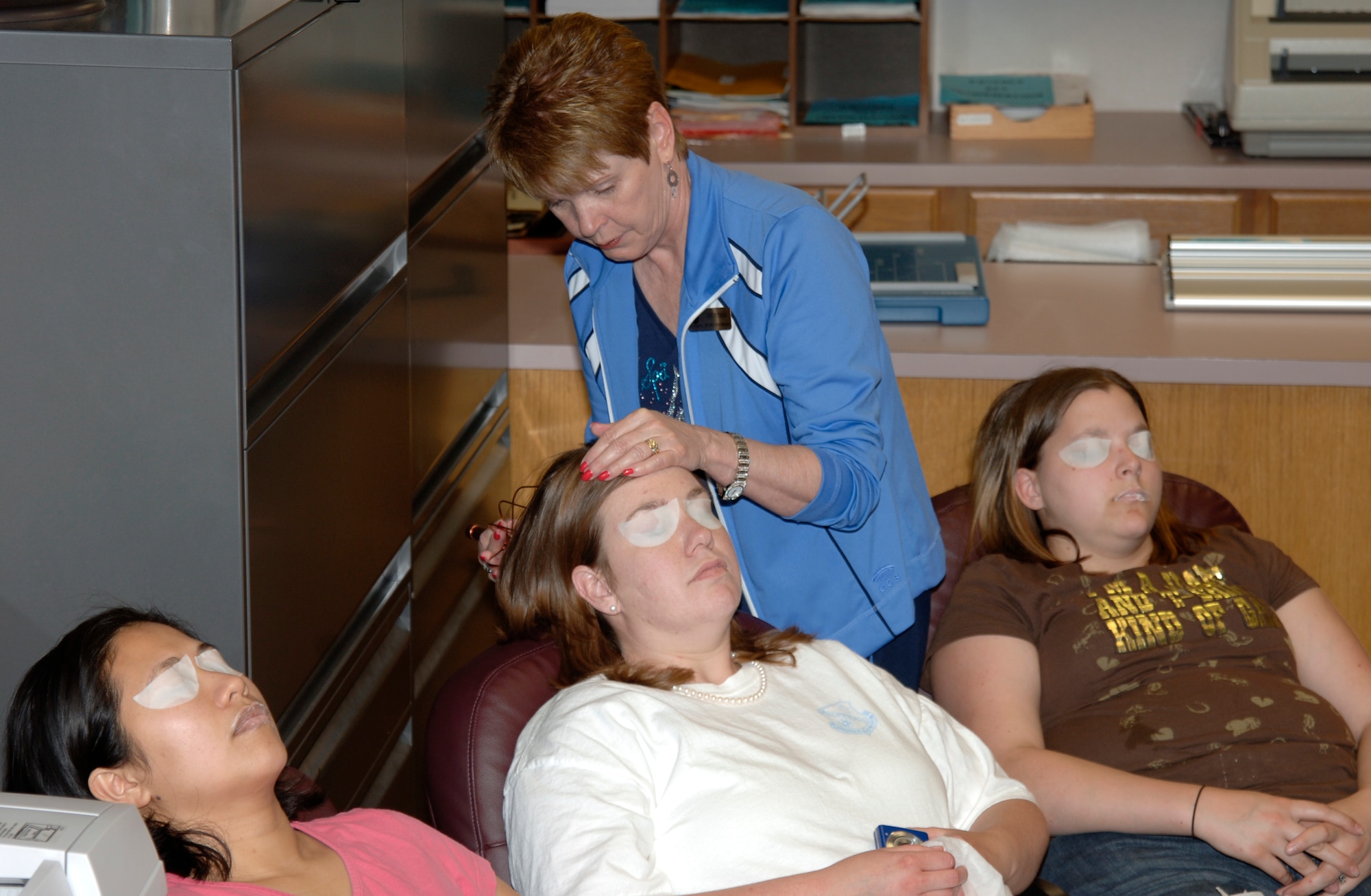 MCCONNELL AIR FORCE BASE, Kan. -- Beauty Specialist, Judy Peterson, uses a scalp massager on Tech. Sgt. Shirley Quevedo, 22nd Maintenance Group, Melissa Flint, and Mollie Denos, Team McConnell members, as they enjoy their sample spa treatment during the Enlisted Spouses Club’s Mom’s Retreat, May 17. The ESC’s Mom’s retreat had multiple events this year including, a sample day spa, scrapbooking, nail painting, a homemade gift card booth, shopping opportunities, refreshments, door prizes, and free credit score checks. (Photo by Airman Justin Shelton)