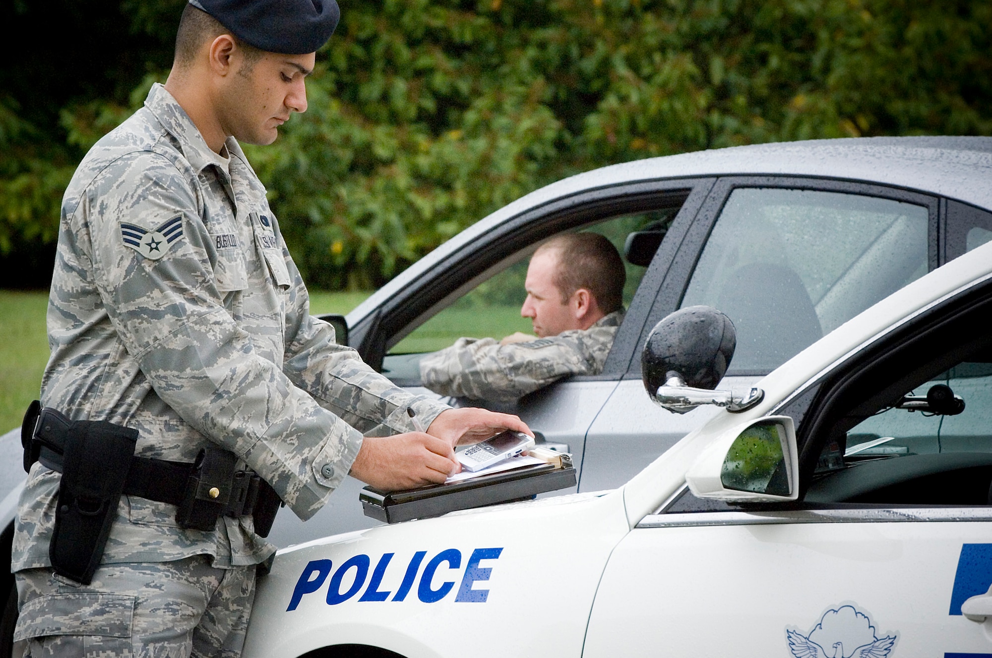 Senior Airman Arnold Bustillo, 62nd Security Forces, demonstrates writing a ticket for driving on base without a seatbelt and talking on a cell phone without a hands-free device during a simulated random vehicle check — both of which violate Department of Defense policy. Fourteen of the 19 Air Force fatalities during the 101 Critical Days of Summer campaign last season were from traffic or vehicle-related accidents. (U.S. Air Force photo/Abner Guzman)