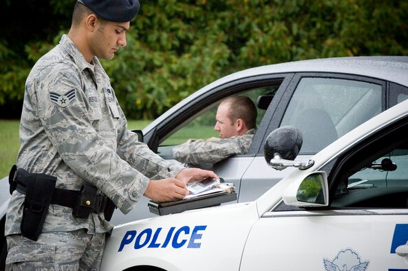 Senior Airman Arnold Bustillo, 62nd Security Forces, demonstrates writing a ticket for driving on base without a seatbelt and talking on a cell phone without a hands-free device during a simulated random vehicle check — both of which violate Department of Defense policy. Fourteen of the 19 Air Force fatalities during the 101 Critical Days of Summer campaign last season were from traffic or vehicle-related accidents. (U.S. Air Force photo/Abner Guzman)