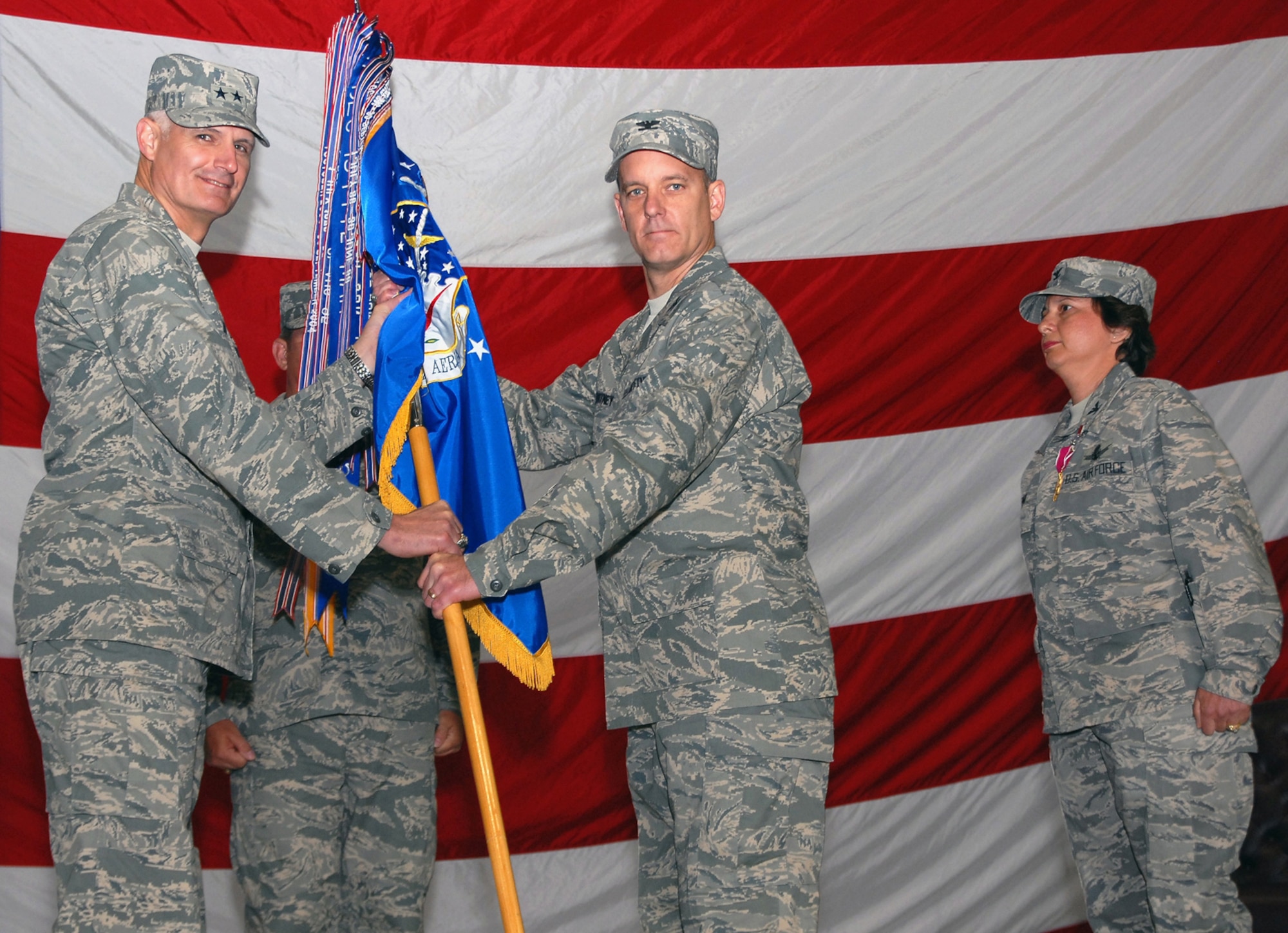 Maj. Gen. Roger Burg (left), 20th Air Force commander passes the 341st Space Wing guidon to incoming  commander Col. Michael Fortney while outgoing commander Col. Sandy Finan looks on. The change of command ceremony was held May 21 in the 3-Bay Hangar. (U.S. Air Force photo/John Turner)