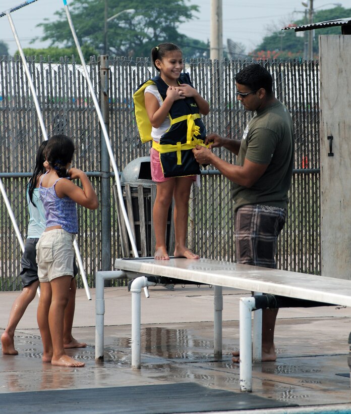 Staff Sgt. Daniel Santiago helps a girl with a life jacket prior to her diving into the pool May 18 at Soto Cano Air Base, Honduras. More than 100 children and staff from Hogar de Guadalupe Orphanage in El Conejo, Honduras, came for a day of fun and relaxation. Sergeant Santiago is assigned to the 612th Air Base Squadron civil engineer flight. (U.S. Air Force photo/Tech. Sgt. John Asselin) 
