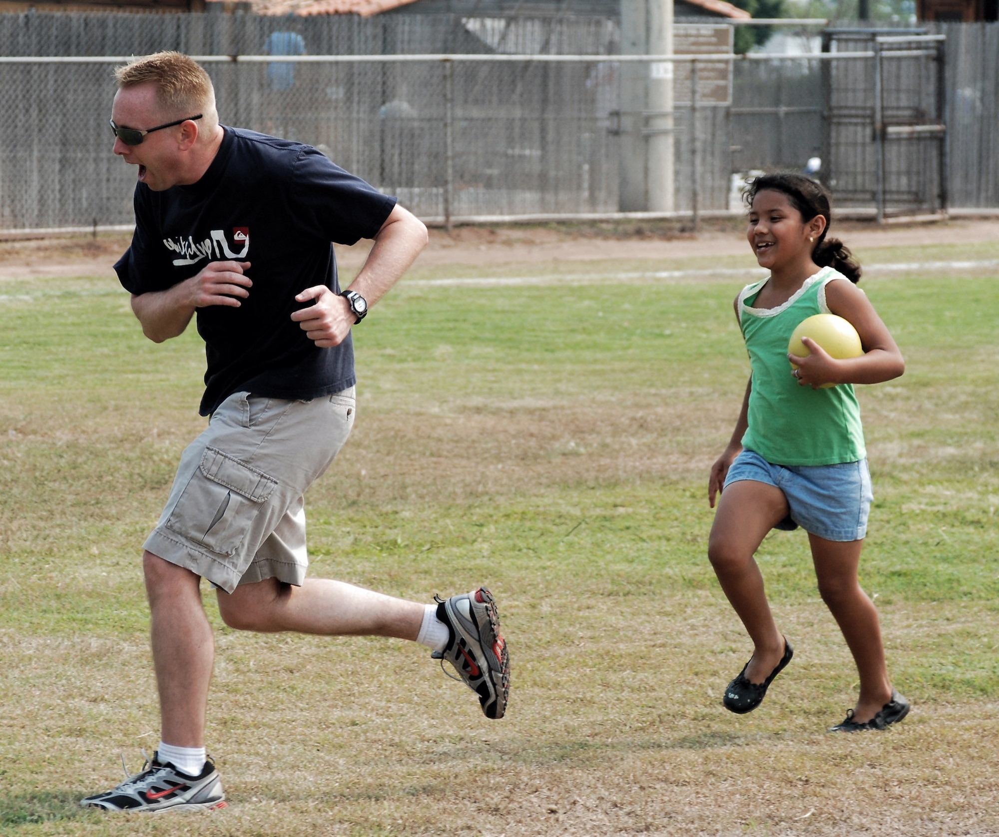 Master Sgt. Jon Callaway plays tag with a girl from the Hogar de Guadalupe Orphanage during a kid's day May 18 at Soto Cano Air Base, Honduras. Members of the 612th Air Base Squadron holds the event yearly to provide a day of fun and games for children of the orphanage the unit sponsors. Sergeant Callaway is the 612th ABS Logistics Flight superintendent. (U.S. Air Force photo/Tech. Sgt. John Asselin) 