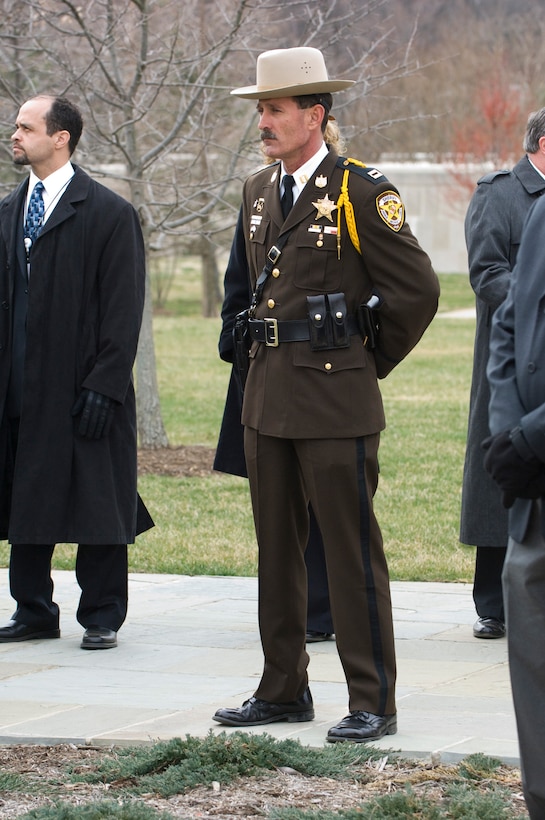 A Prince George's County police captain stands at parade rest, awaiting the funeral procession of Air Force Office of Special Investigations Special Agent Thomas Crowell heading to Arlington National Cemetery. (U.S. Air Force photo/Mike Hastings)