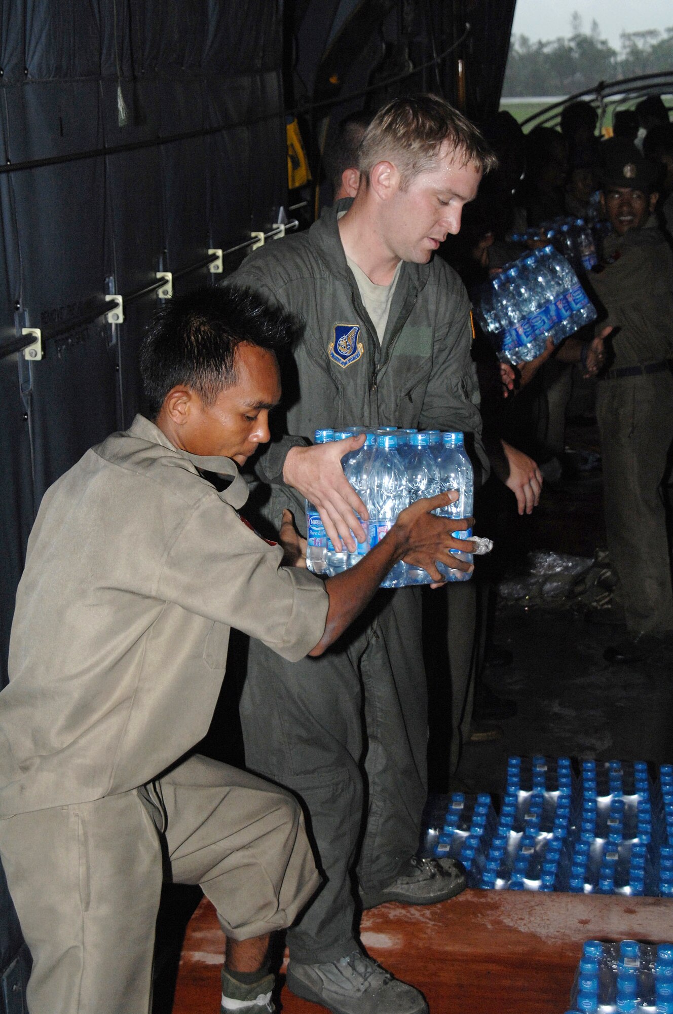 Staff Sgt Joseph Strutton helps a local Burmese man transfer water from a pallet aboard a U.S. Air Force C-130 Hercules May 19 to a truck at the Yangon International Airport in Burma. Sergeant Strutton is with the 374th Airlift Wing from Yokota Air Base, Japan. The relief supplies will be delivered to the citizens of Burma who were devastated by a recent cyclone. (U.S. Air Force photo/Senior Airman Sonya Croston) 