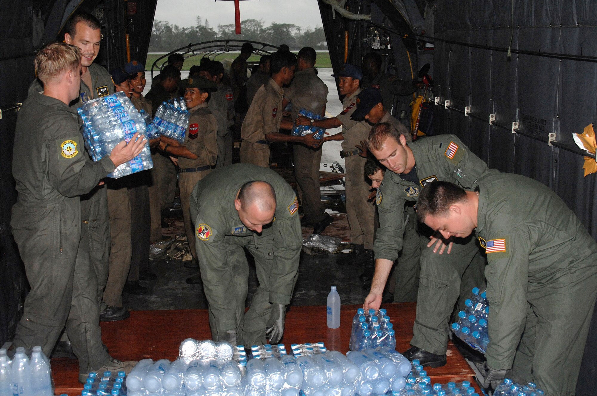 Air Force members from Yokota Air Base, Japan, assist with the delivery of humanitarian relief supplies for the people of Burma May 19 at Yangon International Airport in Burma. Approximately 15,000 pounds of water, water containers and mosquito netting were unloaded from the C-130 Hercules aircraft. The Air Force members are part of the Joint Task Force Caring Response, a multi-service Humanitarian Assistance and Disaster Relief effort for Burmese citizens devastated by a recent cyclone. (U.S. Air Force photo/Senior Airman Sonya Croston) 