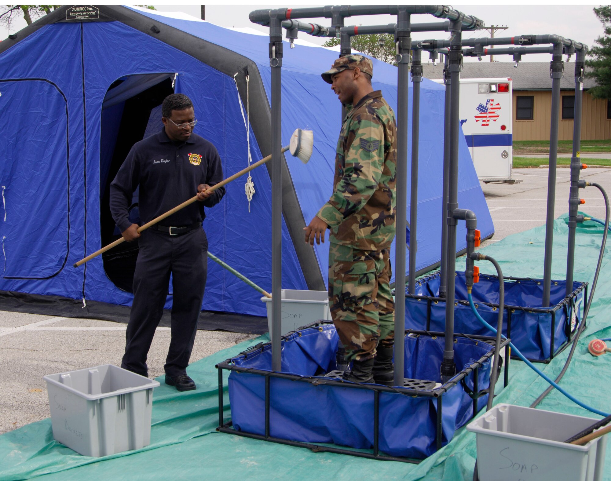 SCOTT AIR FORCE BASE, Ill. -- Ivan Taylor, 375th Civil Engineer Squadron firefighter, does a mock scrub down of Staff Sgt. Michael Satchell, 375th Civil Engineer Squadron crew chief, while they explain to members of the surrounding communities how the emergency decontamination showers work during an event put on by the squadron May 14. (U.S. Air Force photo/Airman 1st Class Wesley Farnsworth)