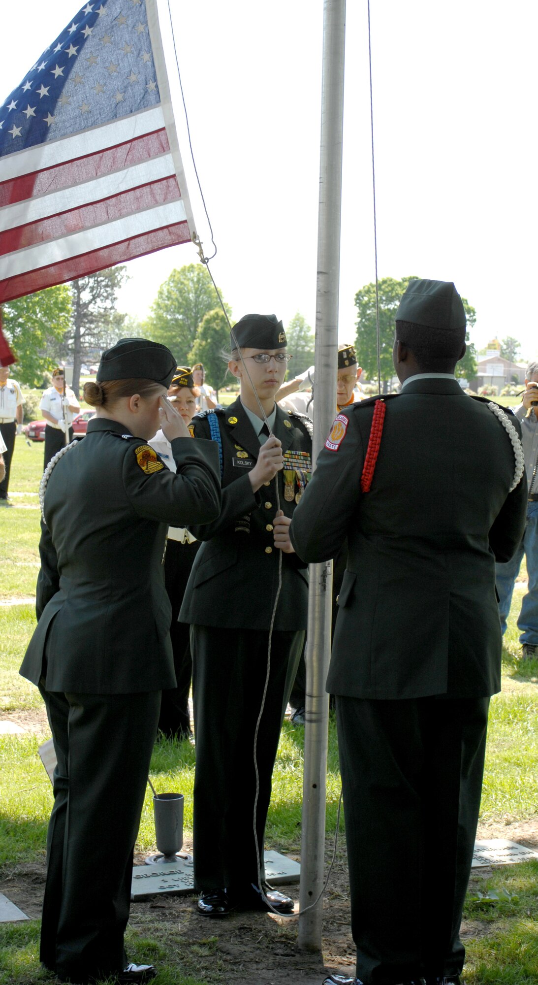 SEDALIA, Mo., - Members of the Smith-Cotton High School JROTC Honor Guard, from left to right, Mallory Graves, Rebecca Kolsky and Paris Potts, lower the flag to half staff during the 20th Annual Whiteman Memorial Wreath Laying Ceremony in Sedalia's Memorial Park Cemetery. (U.S. Air Force/1st Lt. Matthew Miller)