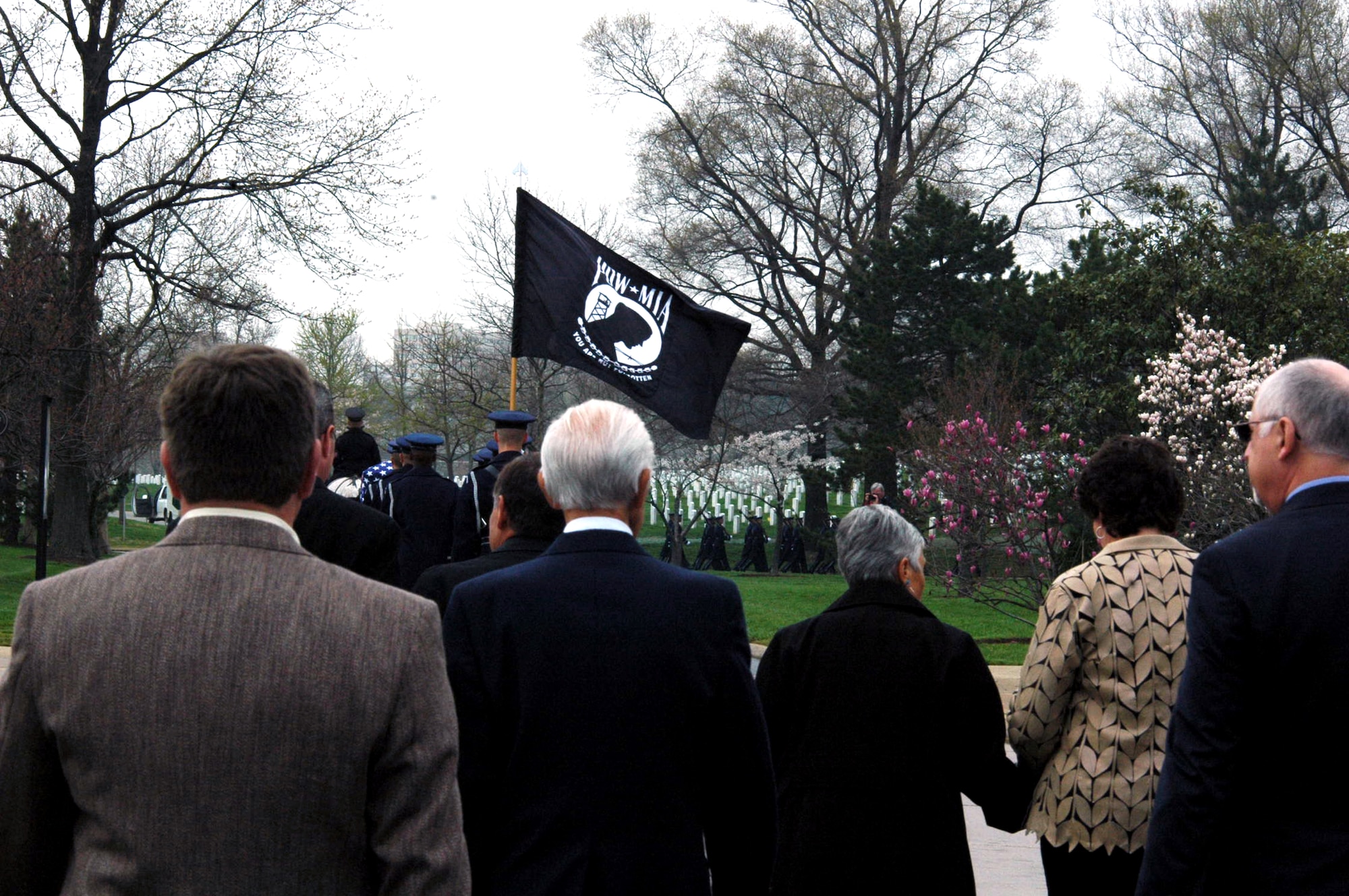 Family members of Maj. Robert F. Woods walk behind the horse-drawn caisson during the funeral for Major Woods at Arlington National Cemetery, Va., on April 9, 2008. This card was distributed by the family of Maj. Robert F. Woods during his funeral at Arlington National Cemetery on April 9, 2008.  On June 26, 1968, Major Woods disappeared in the Quang Binh Province in Vietnam after the 02-A Skymaster he was flying crashed in a remote mountainous region.  A native of Salt Lake City, Utah, Major Woods was in the military for 20 years when he disappeared. His career began in June 1948 as an enlisted aircrew member on a C-74 Globemaster in the Berlin Airlift.  In 1951 he became an officer and a pilot flying KC-97 Stratotankers in the Korean Conflict.  In Vietnam, he served as a forward air controller in the Skymaster with the 20th Tactical Air Support Squadron in DaNang Air Base, South Vietnam. He earned his first of eight Air Medals in Korea and also earned the Distinguished Flying Cross and Bronze Star for his service in Vietnam.  On April 9 he was laid to rest at Arlington nearly 40 years after he disappeared.  (U.S. Air Force Photo/Tech. Sgt. Scott T. Sturkol)  