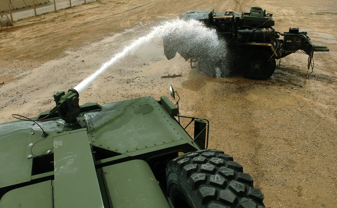 Members of the 332nd Expeditionary Civil Engineer Squadron and 8th Ordnance Company fire departments extinguish a vehicle fire with a hood mounted turret hose May 19 at Balad Air Base, Iraq. Due to the variety of aircraft and tactical vehicles located on Balad AB, practical application of pump and roll procedures are invaluable. Pump and roll is the process of fighting a fire while still in motion. (U.S. Air Force photo/Senior Airman Julianne Showalter) 