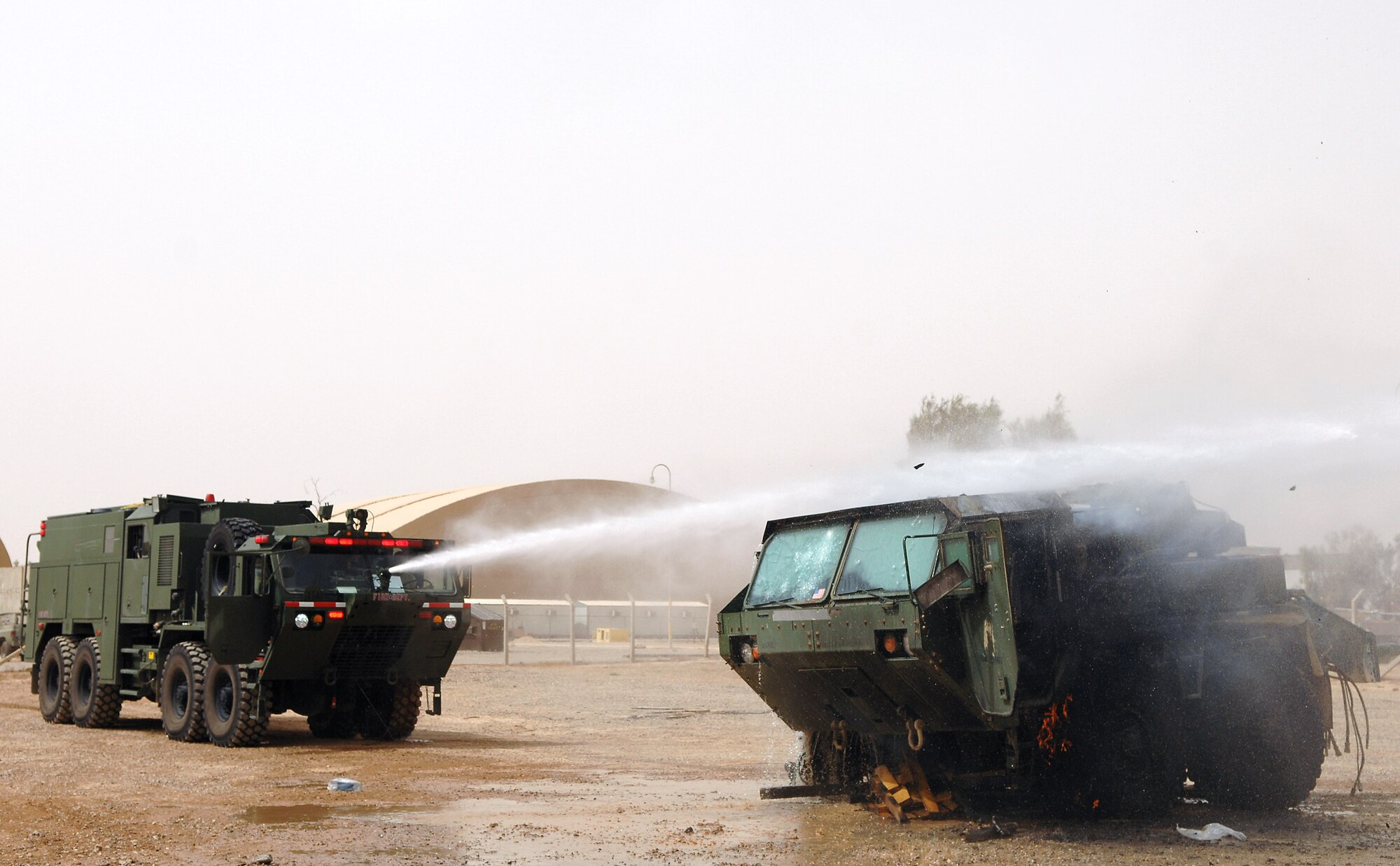 Members of the 332nd Expeditionary Civil Engineer Squadron and 8th Ordnance Company fire departments put out a vehicle fire with a bumper mounted turret hose May 19 at Balad Air Base, Iraq. Pump and roll procedures, which encompass the ability to drive and fight a fire simultaneously, are vital to extinguishing vehicle fires. Doing practical applications of firefighting techniques that mimic possible real-world situations is the best way to ensure the firefighters are prepared at all times. (U.S. Air Force photo/Senior Airman Julianne Showalter) 

