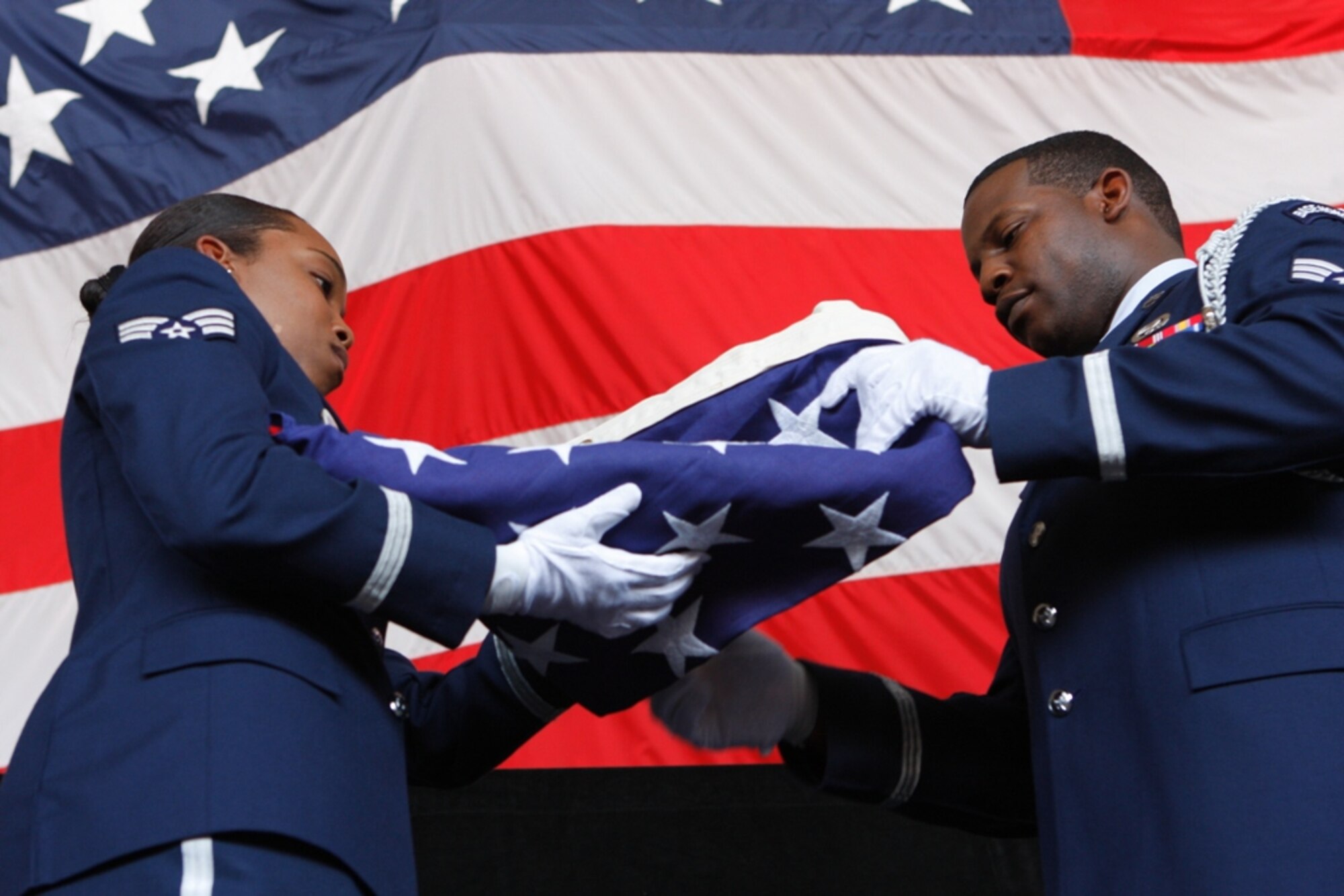 Senior Airmen Tara Austin and Barry Clark, 482nd Fighter Wing Honor Guard members, perform a formal flag folding during Col. Randall G. Falcon’s retirement ceremony on May 18. The ceremony doubled as a change of command welcoming Col. William B. Binger as new commander of the 482nd FW. (Courtesy photo by Albert Siegel)