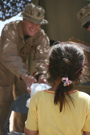 Petty Officer 3rd Class Joshua Moore, religious programmer, 2nd Battalion, 3rd Marine Regiment, Regimental Combat Team 1, hands a teddy bear to an Iraqi girl May 21, in Sitcher, Iraq, during a cooperative medical engagement. More than 1,000 teddy bears were donated from the Oahu Chapter of Zeta Delta Society in Hawaii, to give to the children of Iraq. (Photo by Cpl. Chadwick deBree)