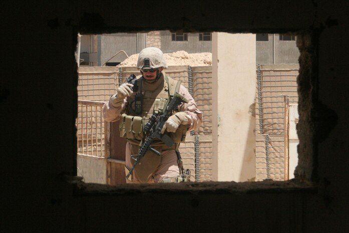 Gunnery Sgt. Gary M. Gonzales, the assistant team leader with Detachment 1, Civil Affairs Team 5, 2nd Battalion, 11th Marine Regiment, Regimental Combat Team 5, inspects the outside of a building in Anah, Iraq, May 20, that is being refurbished after Coalition forces relocated. The building was previously a hotel that belonged to the local government. Until recently, the hotel was being used as a combat outpost and joint community center.