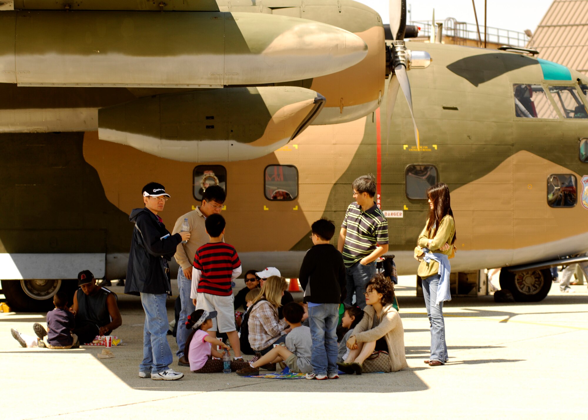 Spectators use the shade from a C-130 aircraft's wing at the 2008 Joint Service Open House hosted by Andrews Air Force Base, Md., May 17th.   This year?s event will have demonstrations by the Navy Blue Angels and the Army's Golden Knights.  Once again the JSOH will host a wide variety of both military and civilian air and ground demonstrations. To include the Air Force's newest and the world's most advanced fighter jet, the F-22A Raptor. (U.S. Air Force photo by Tech Sgt. Suzanne M. Day)(Released)
