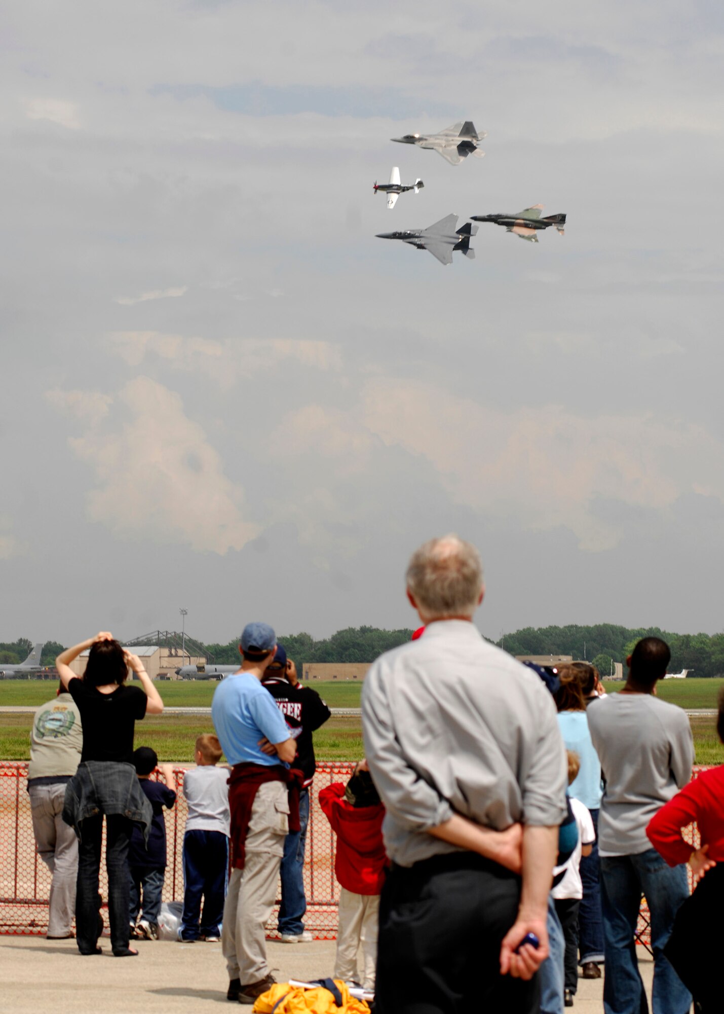 The crowd watches a formation fly by at the 2008 Joint Service Open House hosted by Andrews Air Force Base, Md., May 16th.   This year?s event will have demonstrations by the Navy Blue Angels and the Army's Golden Knights.  Once again the JSOH will host a wide variety of both military and civilian air and ground demonstrations. To include the Air Force's newest and the world's most advanced fighter jet, the F-22A Raptor. (U.S. Air Force photo by Tech Sgt. Suzanne M. Day)