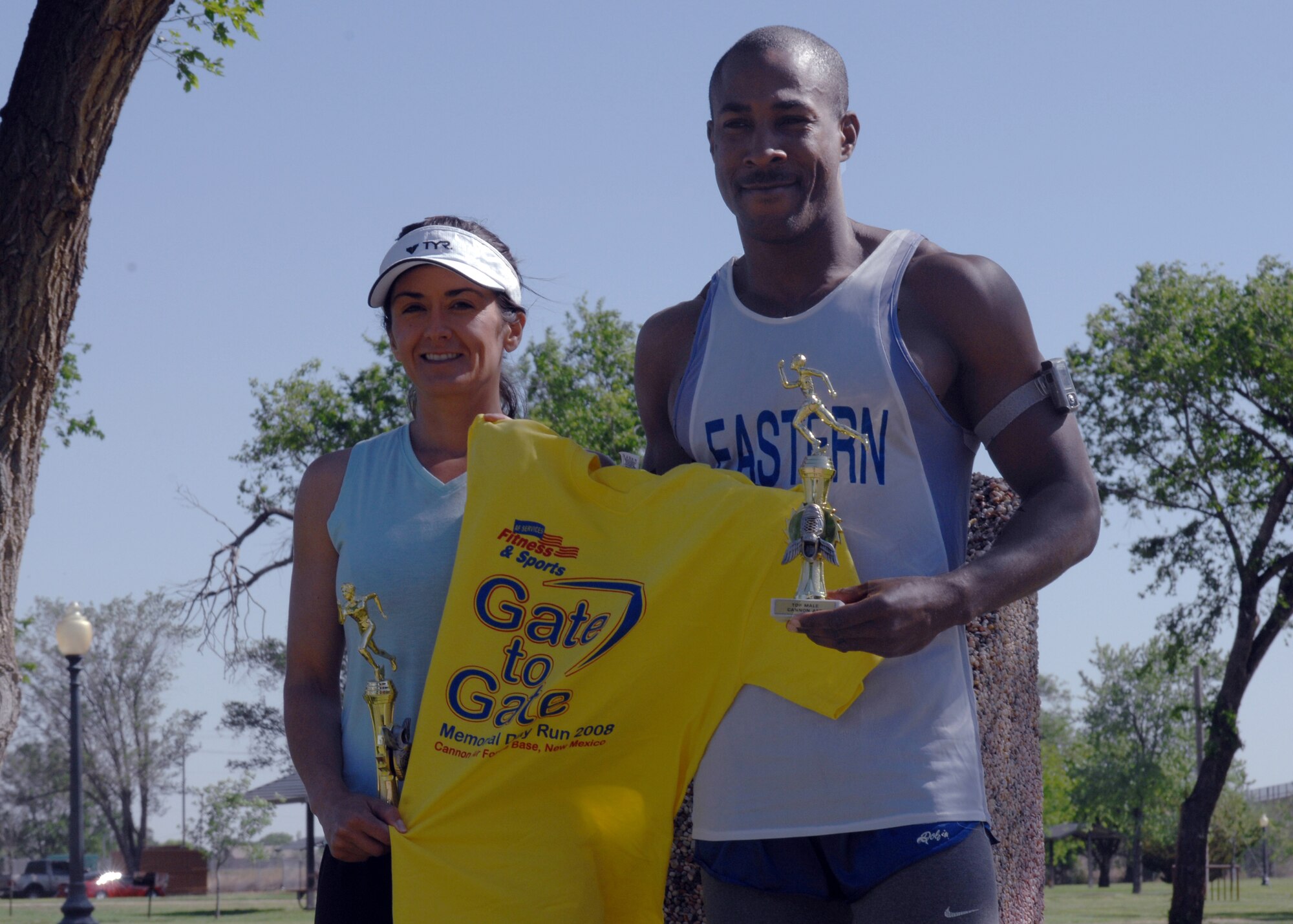 CANNON AIR FORCE BASE N.M.-- Kathy Leahy and Staff Sgt. Eric Schmidt, 27th Special Operations Civil Engineer Squadron, display a t-shirt and the trophies they won the top runners in their categories of the annual Gate-to-Gate Run on May 22.  Airmen and civilians ran 5.5 miles to honor fallen warriors as part of the upcoming Memorial Day observances.  (U.S. Air Force photo by Airman 1st Class James R. Bell)