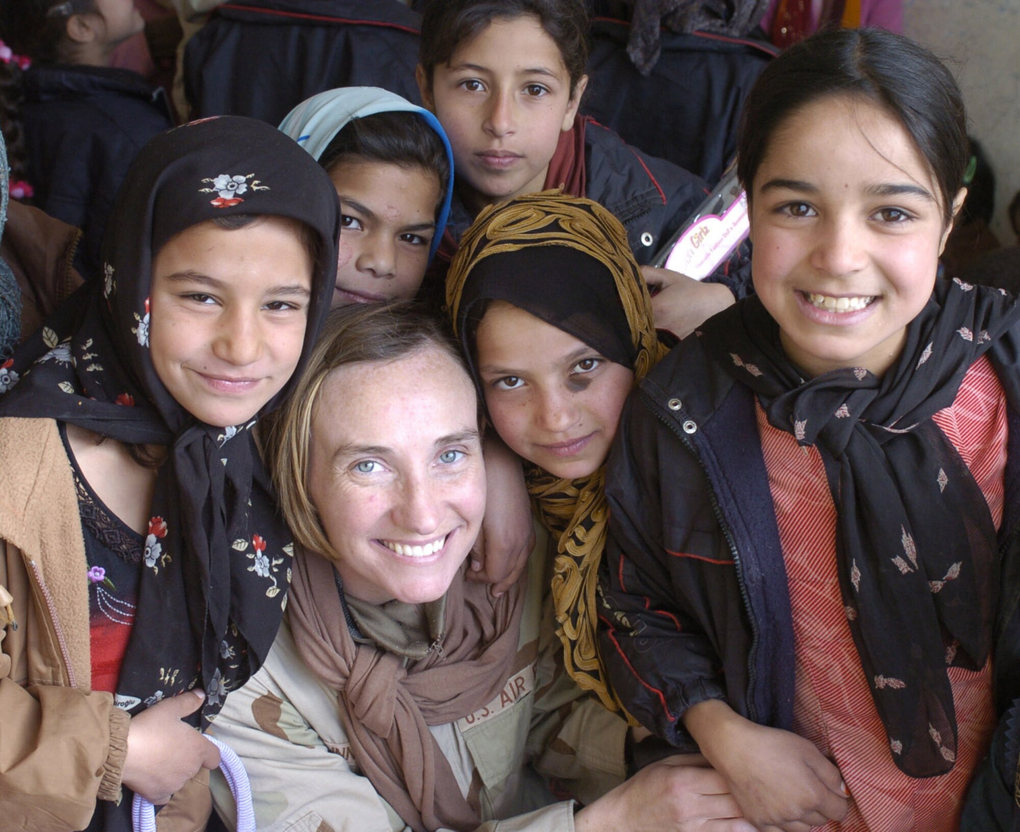 1st Lt. Elaine Hunnicutt, a public affairs officer with Combined Forces Command Afghanistan, picured with children in a rural Afghani village in December 2004. (U.S. Air Force photo)