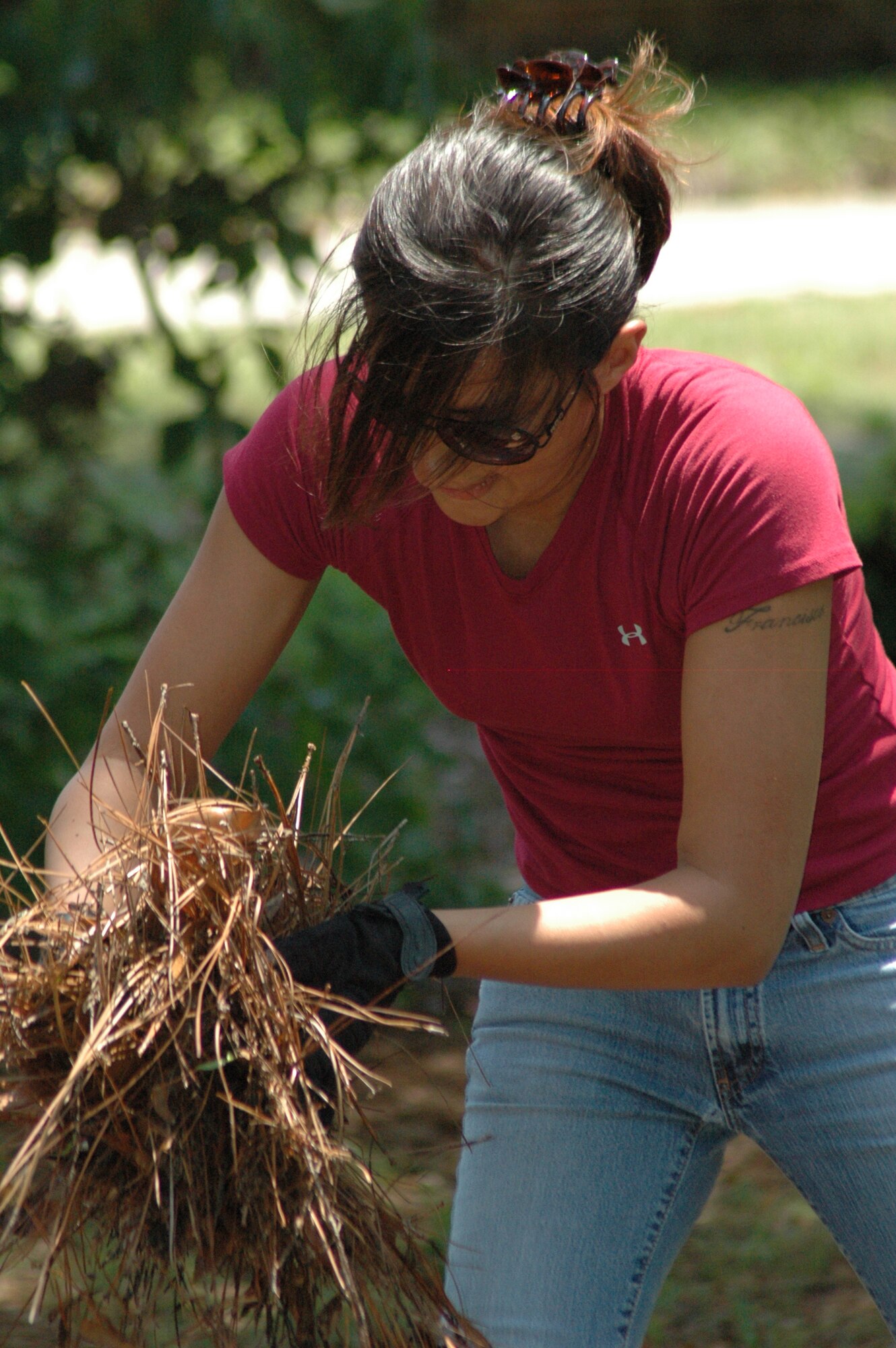 EGLIN AIR FORCE BASE -- Staff Sgt. Nancy Chavez-Mozingo, 96th Medical Operations Squadron, throws pine needles into a barrel while gardening for the volunteer cleanup at Bob Hope Village. The premise of the event was to aid the residents with minor chores and needs.