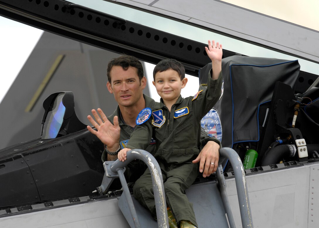 Maj Max Moga, F-22 Raptor Pilot, waves with Brandon Leach, during his tour of the Joint Service Open House. Branedon got a personalized tour of things such as the 1st Helicopter Squadron, the F-22 Raptor and the Delta 757 that were all here is support of the show. (U.S. Air Force photo by Senior Airman Renae Kleckner)(released)