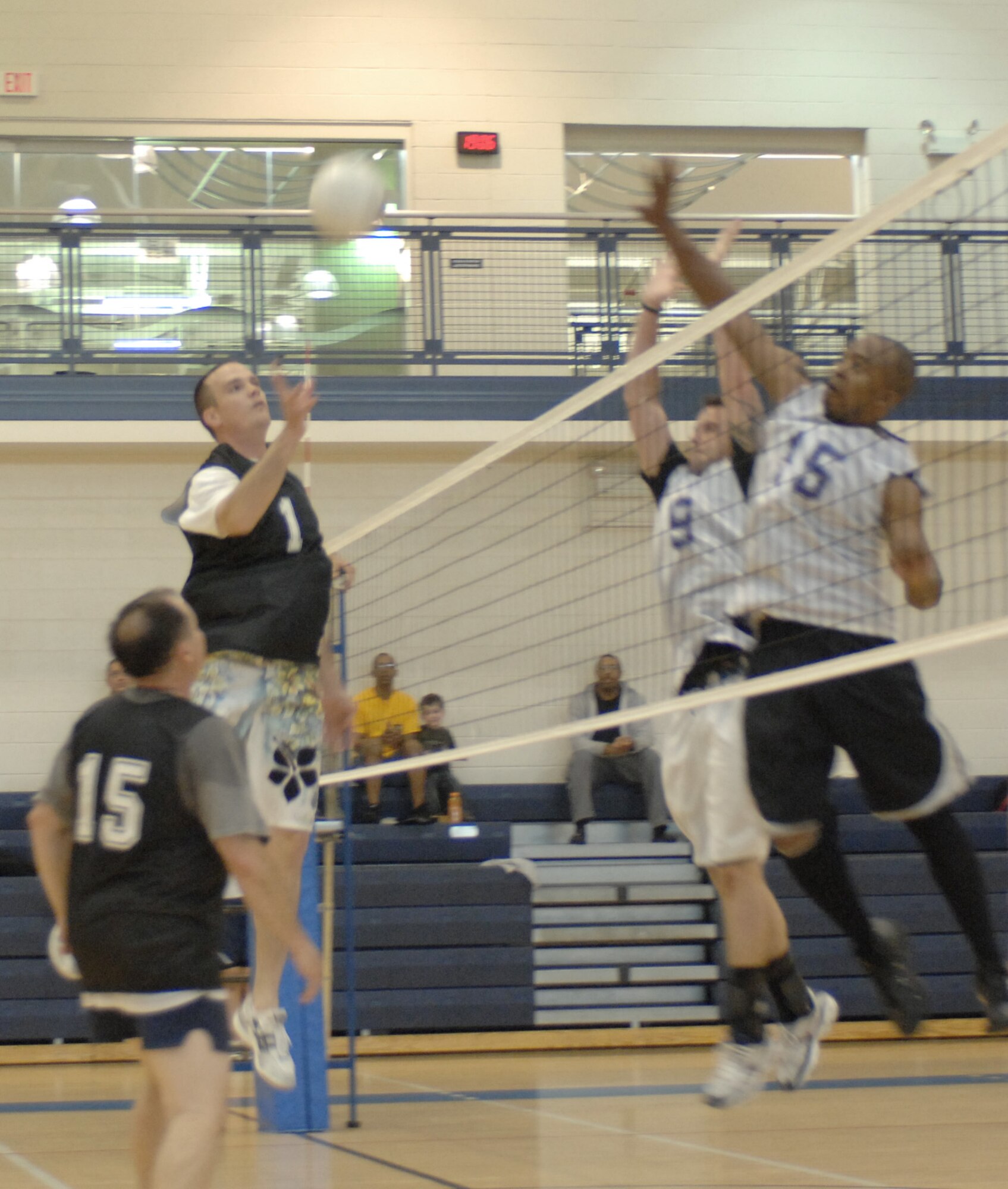 LANGLEY AIR FORCE BASE, Va. -- Tech. Sgt. Rich Shipman (number one), 1st Contracting Squadron,  jumps  up to hit the volleyball while Tech. Sgt. Brandon Gallant (number nine) and Staff Sgt. Kevin Moore (number 15), 735th Supply Chain Management Group, defend the net during the intramural championship game May 21. The 735th SCMG team won the game 25 to 18 against the Air Combat Command Operations Directorate team to become Langley’s intramural volleyball champions. (U.S. Air Force photo/Tech. Sgt. April Wickes)